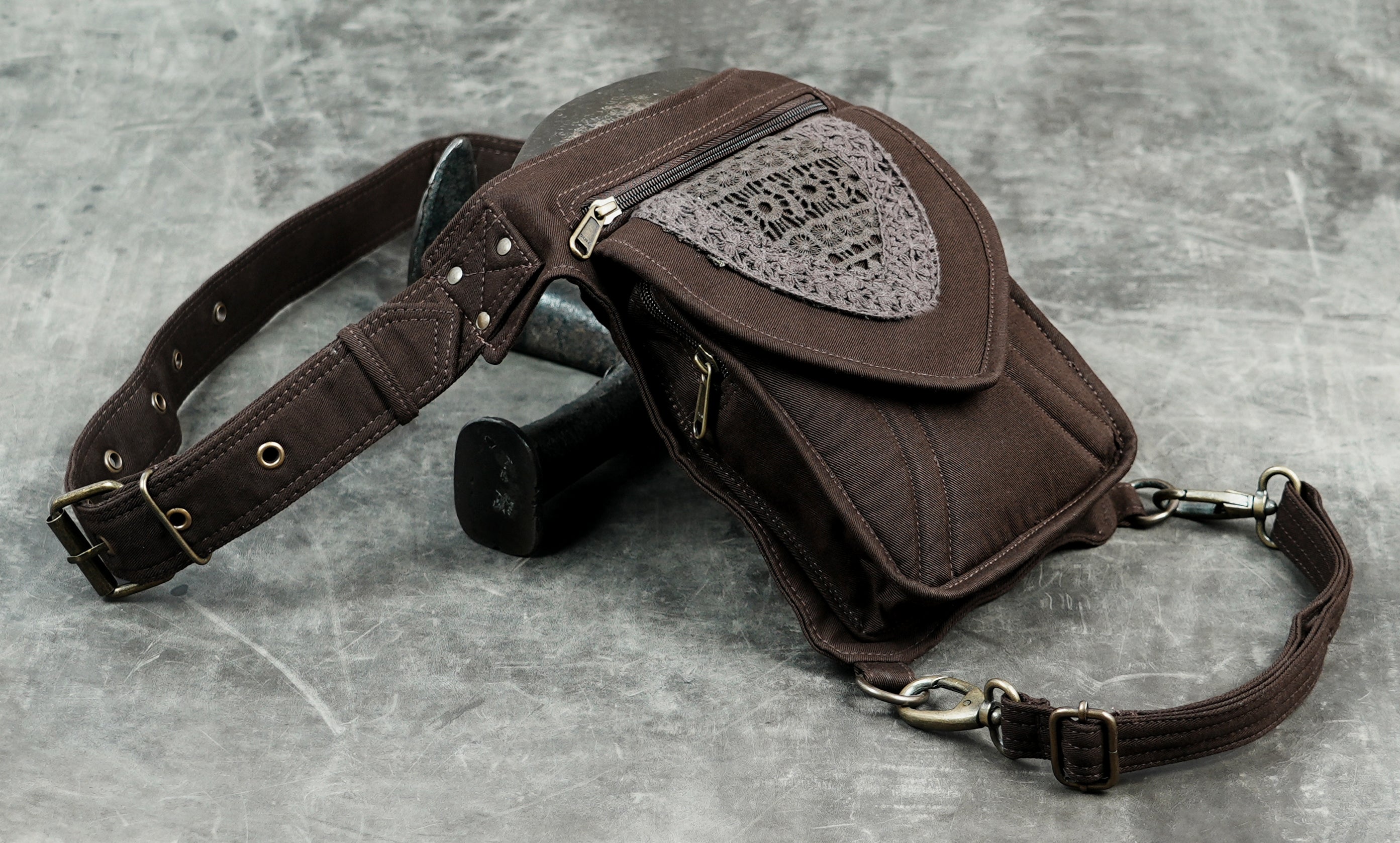 Brown cotton waist thigh belt bag with lace heart pocket, top view on concrete surface