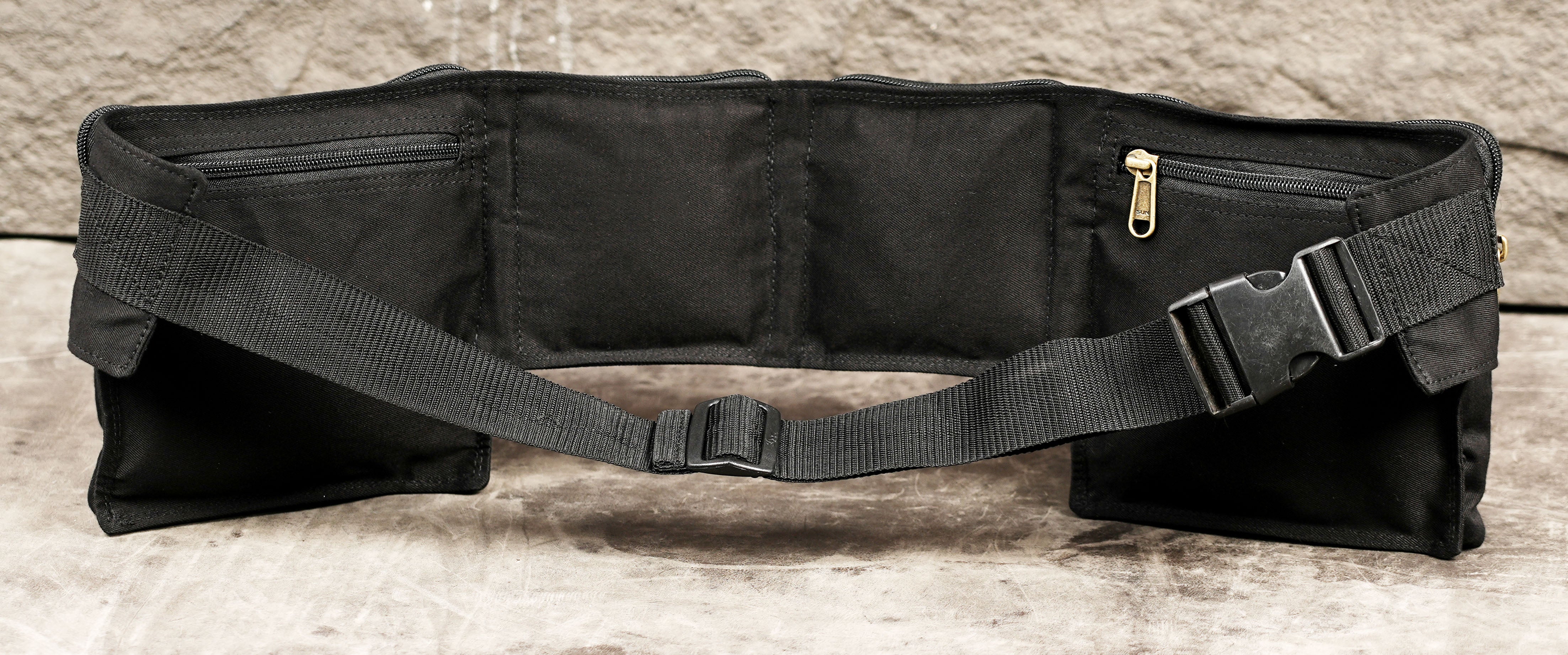 Minimalist black utility waist belt flat lay on concrete background