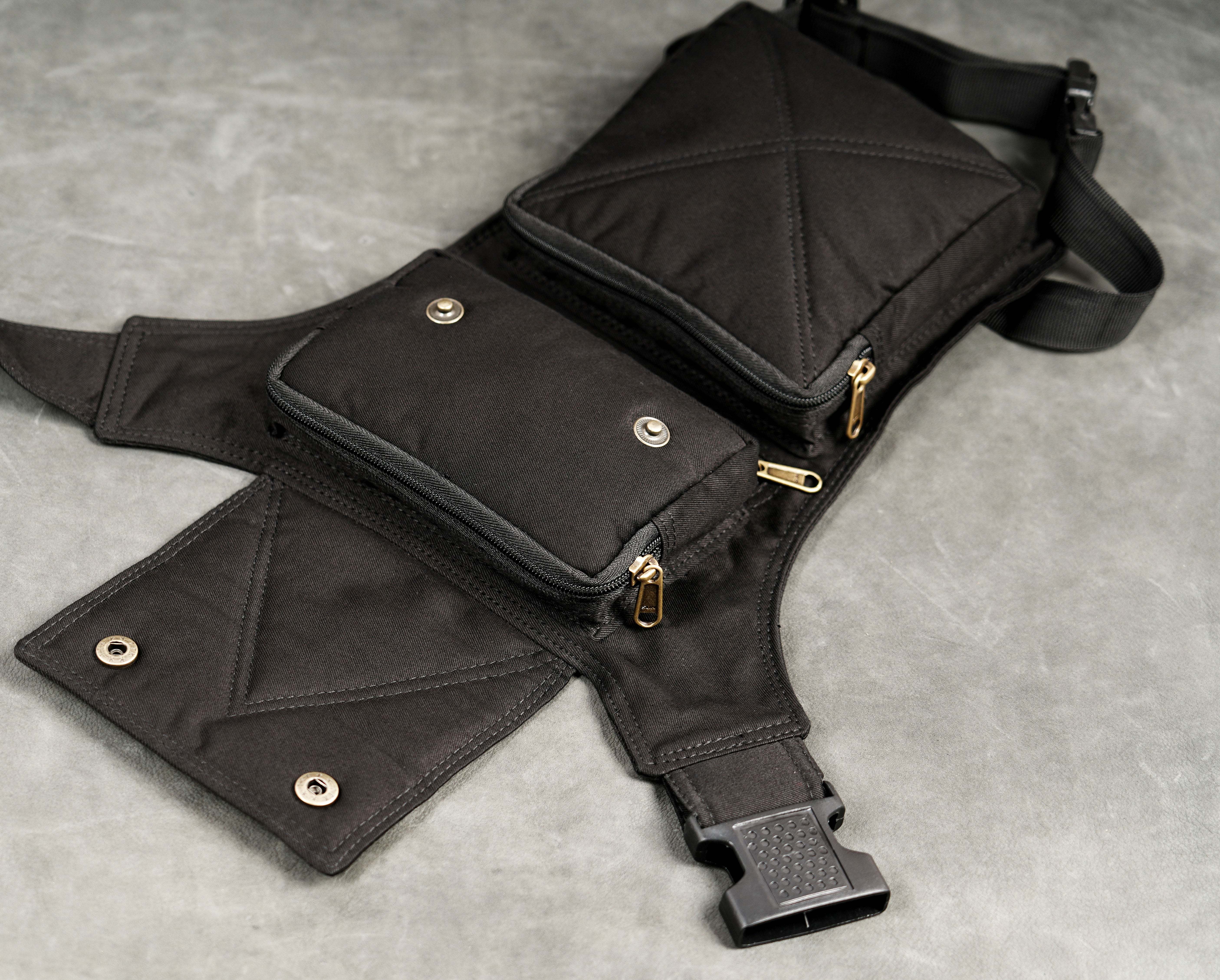 Black drop leg waist bag with front zipper pocket and flap closure