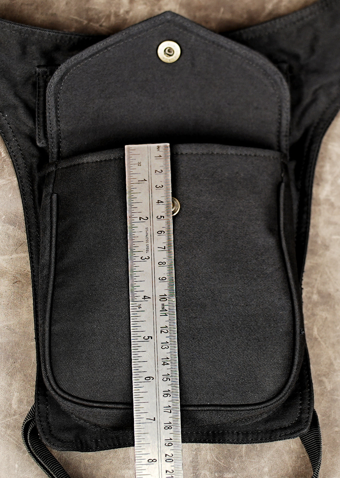 Black canvas fanny pack with thigh strap and front flap pocket.