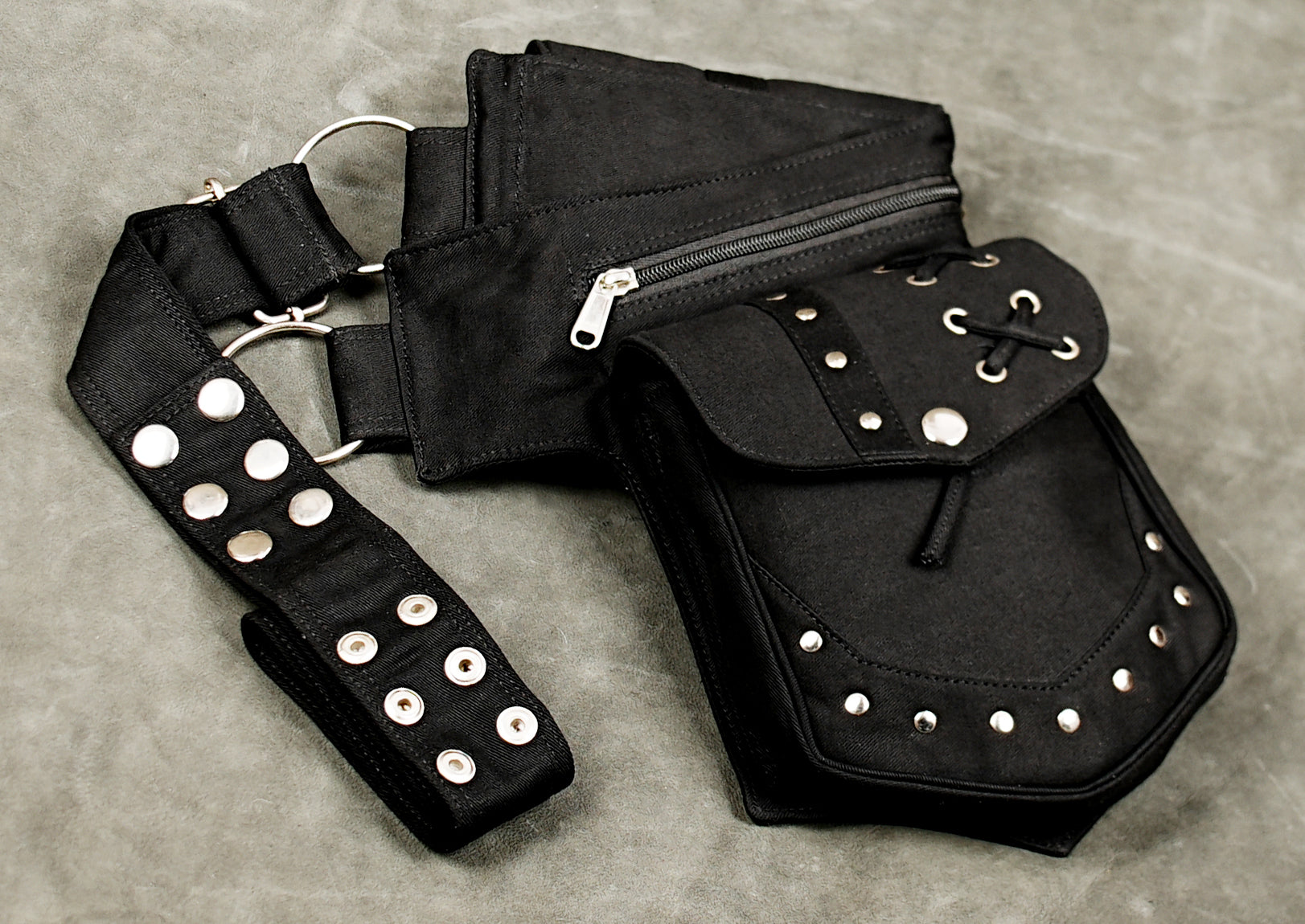 Women's black cotton festival belt bag with metal eyelets and studded pouches for rave clothing.