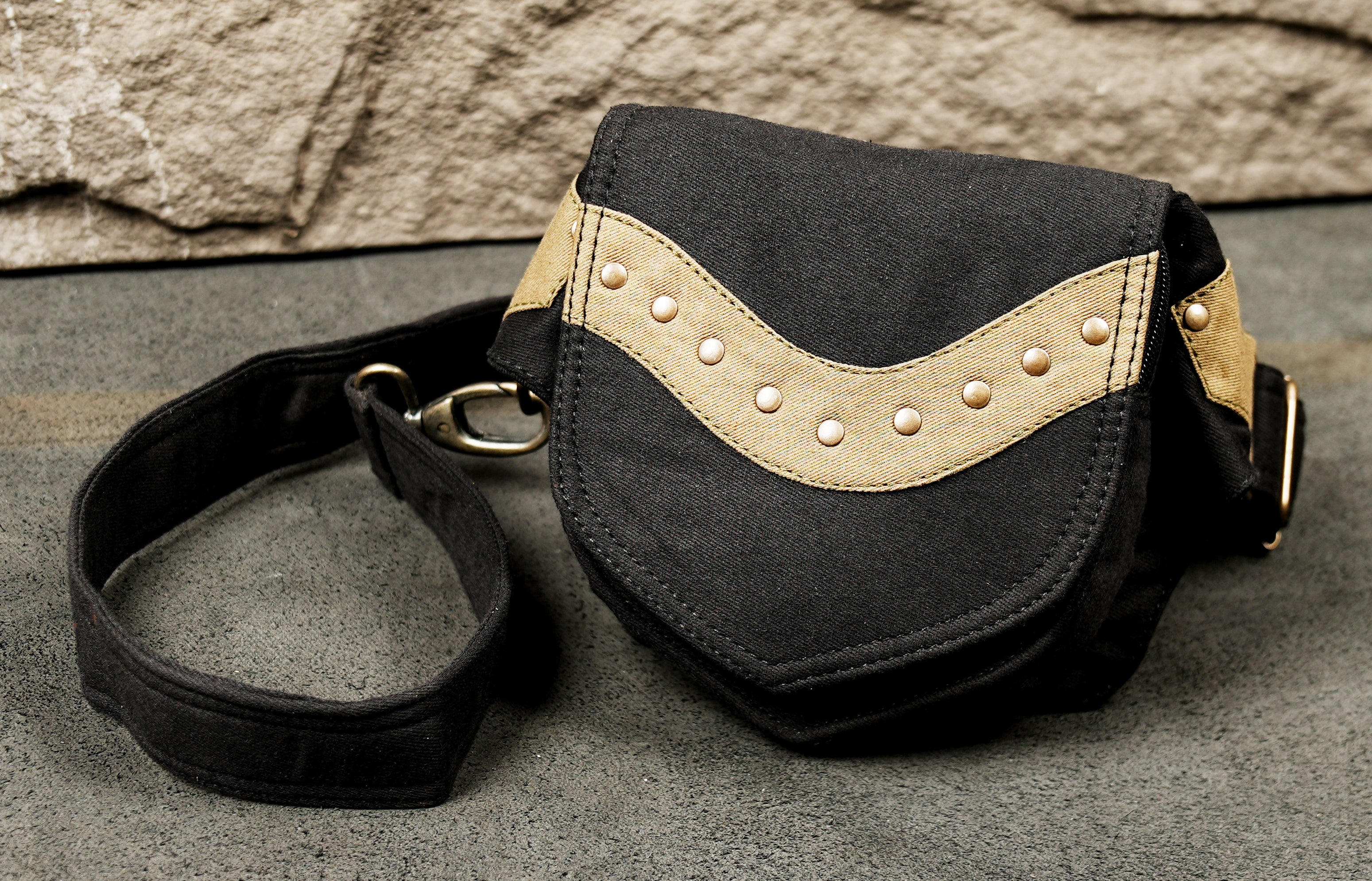 A flat lay of a minimalist black fanny pack (USA) / belt bag with unique, light-colored hardware accents.