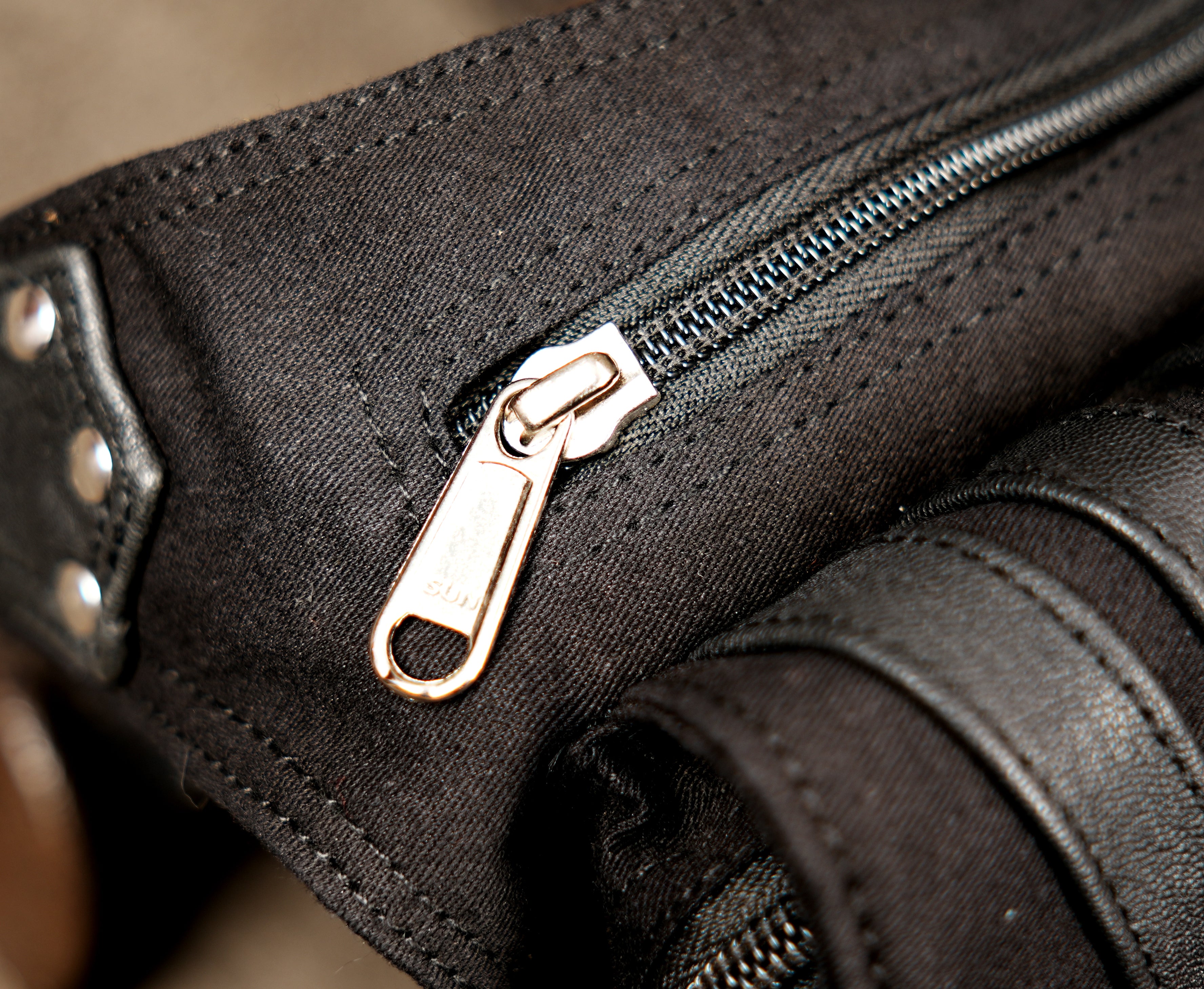 Artisanal cotton drop-leg pouch with leather-look trim, rivets, and metal O-rings.