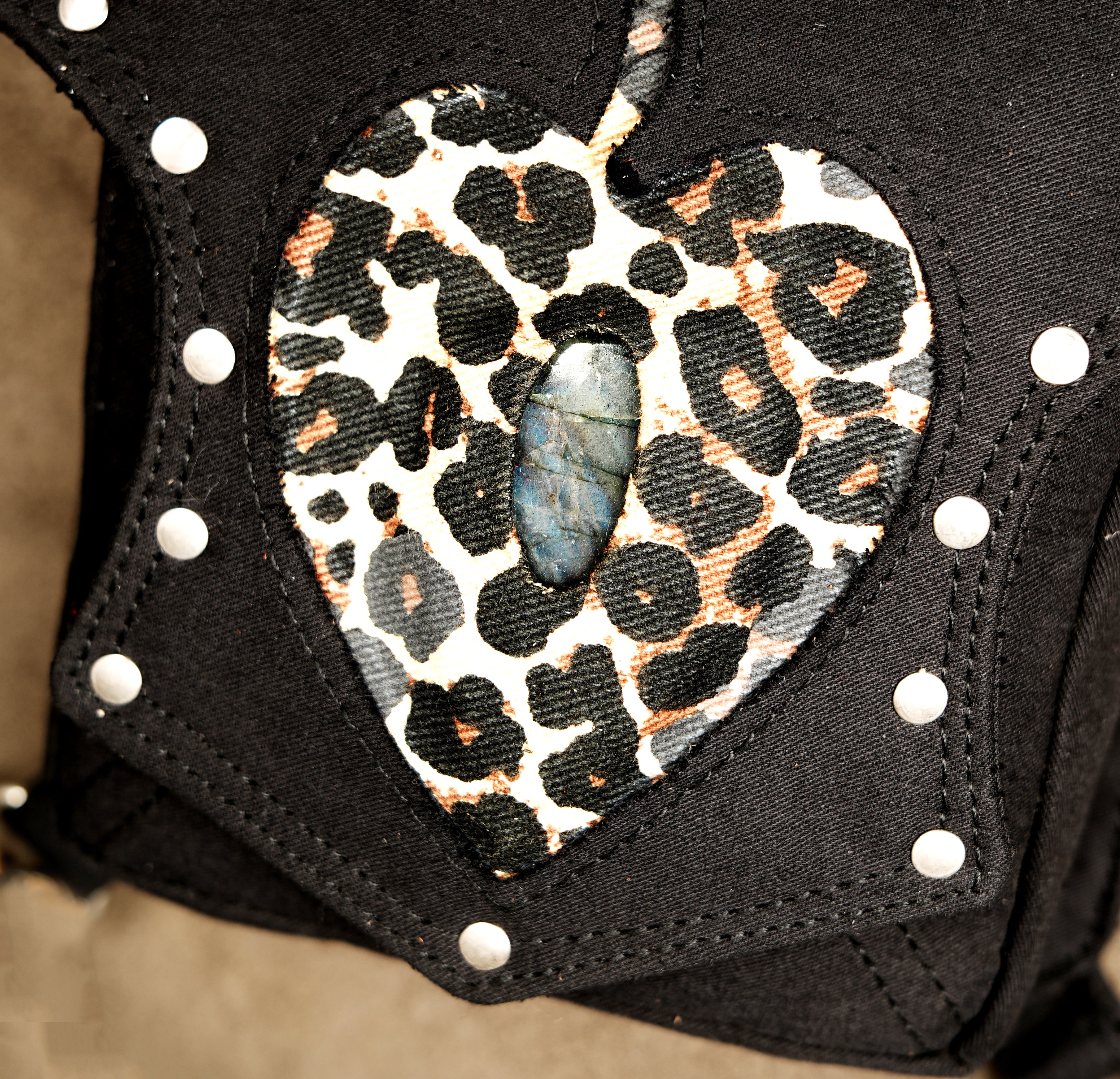 The central flap of this cotton bag features a prominent leopard print heart with a central gem.