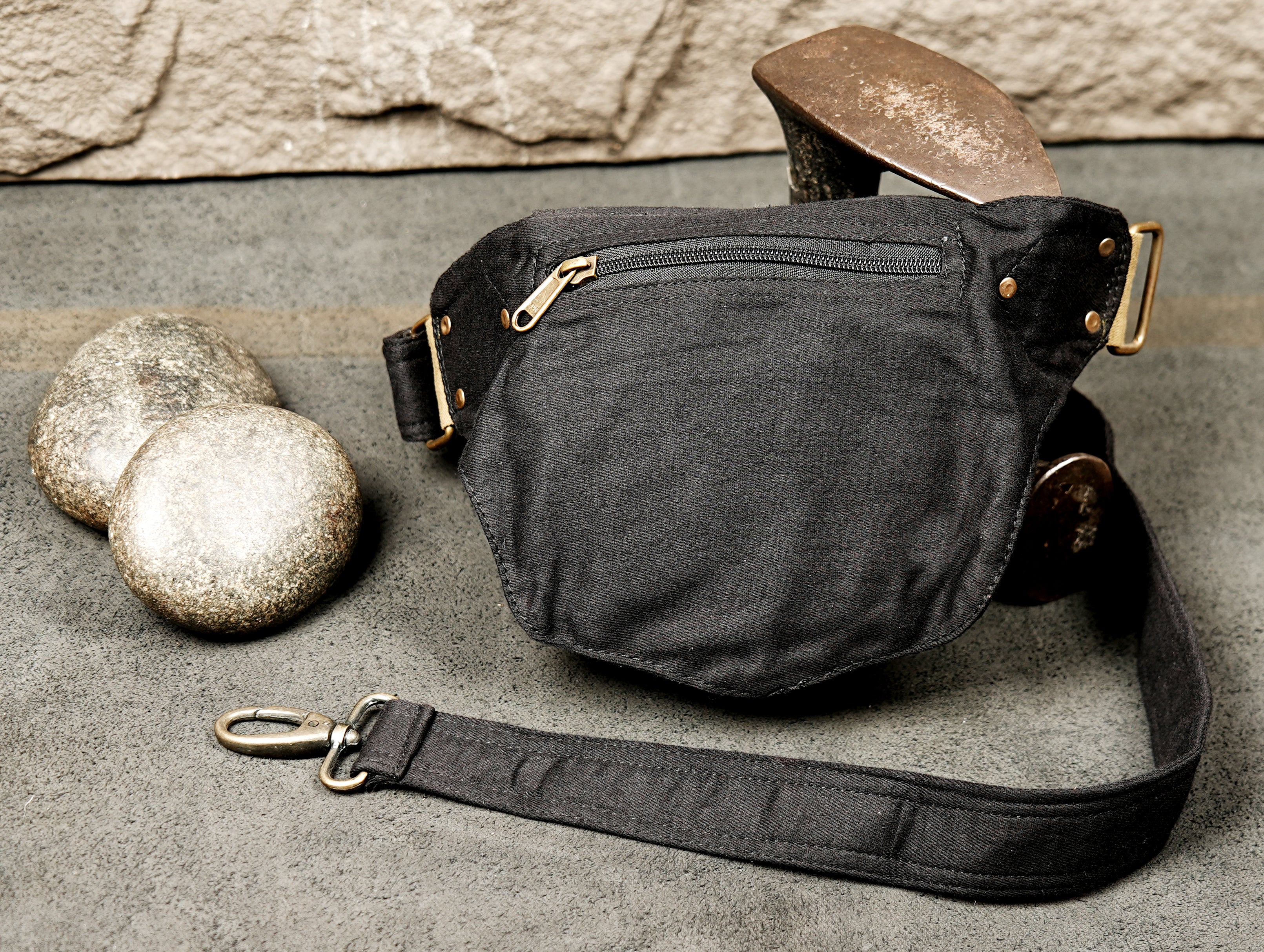 Focus on the secure closure flap of this black cotton waist bag, featuring decorative studs.