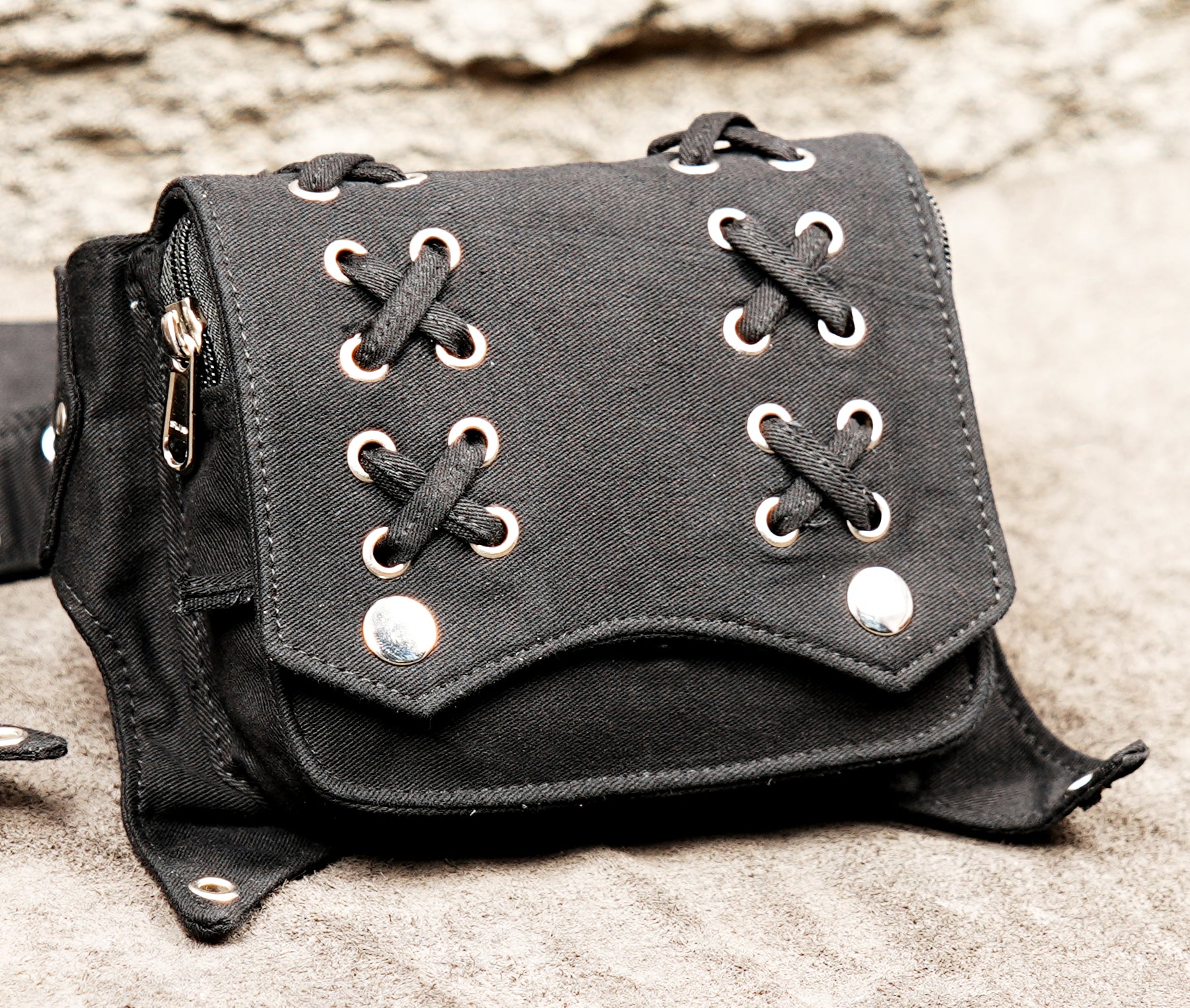 Adjustable waist pack with two large pockets and decorative grommet strap.