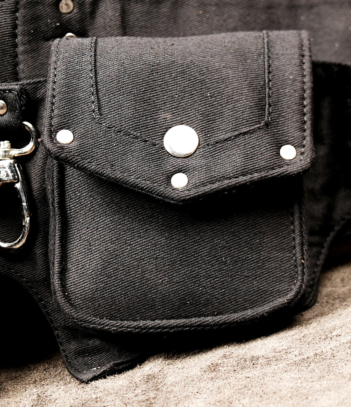 Multi-compartment hip pack in black heavy-gauge cotton canvas, shown against a neutral concrete texture.