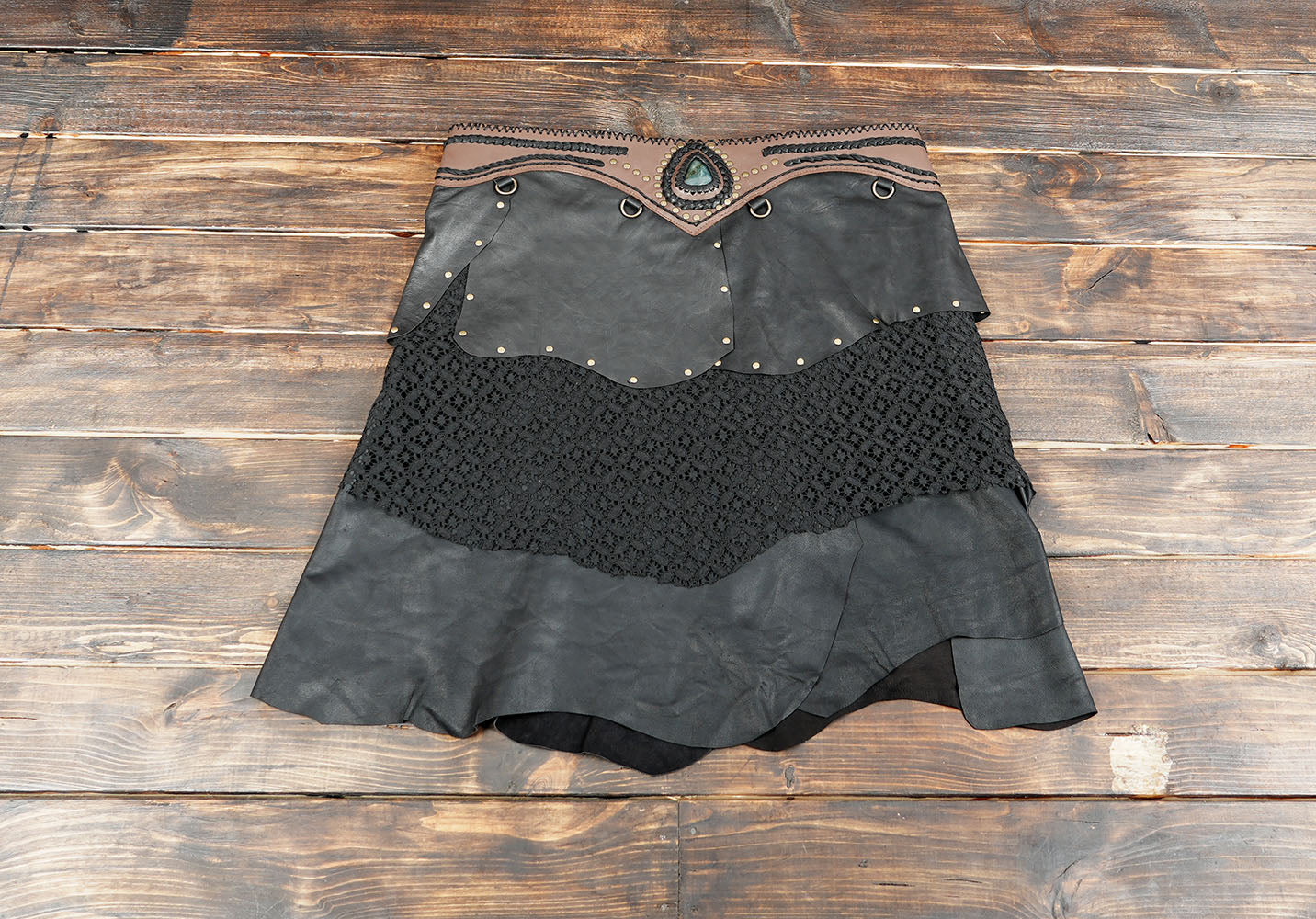 Boho style women’s skirt with black leather, lace fabric, and brown waistband detail with gemstone accent.