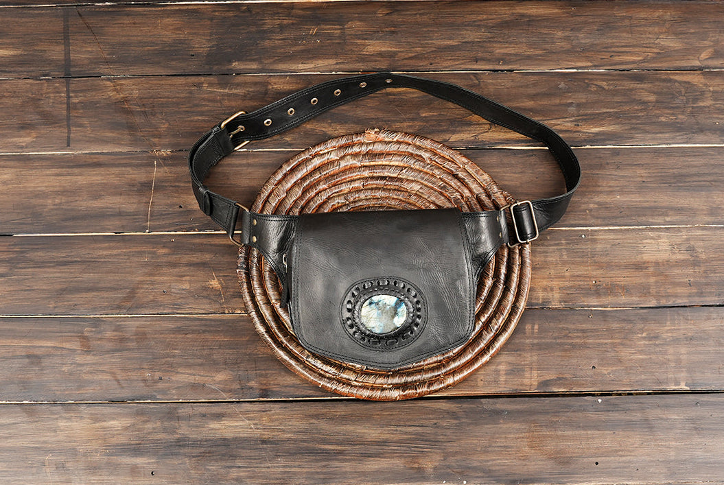 Leather waist belt bag with gemstone detail displayed on wooden background