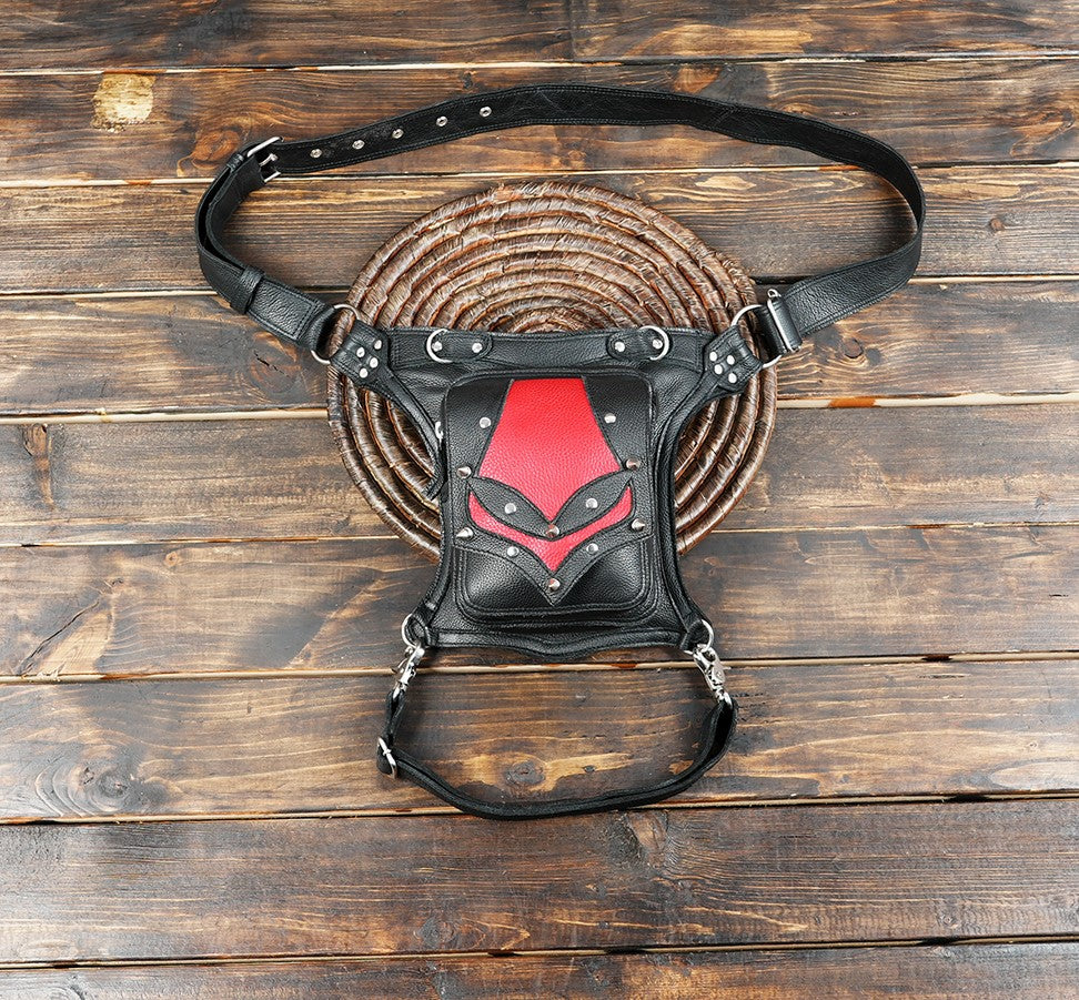 Black and red leather waist thigh belt bag with rivet details on wooden background