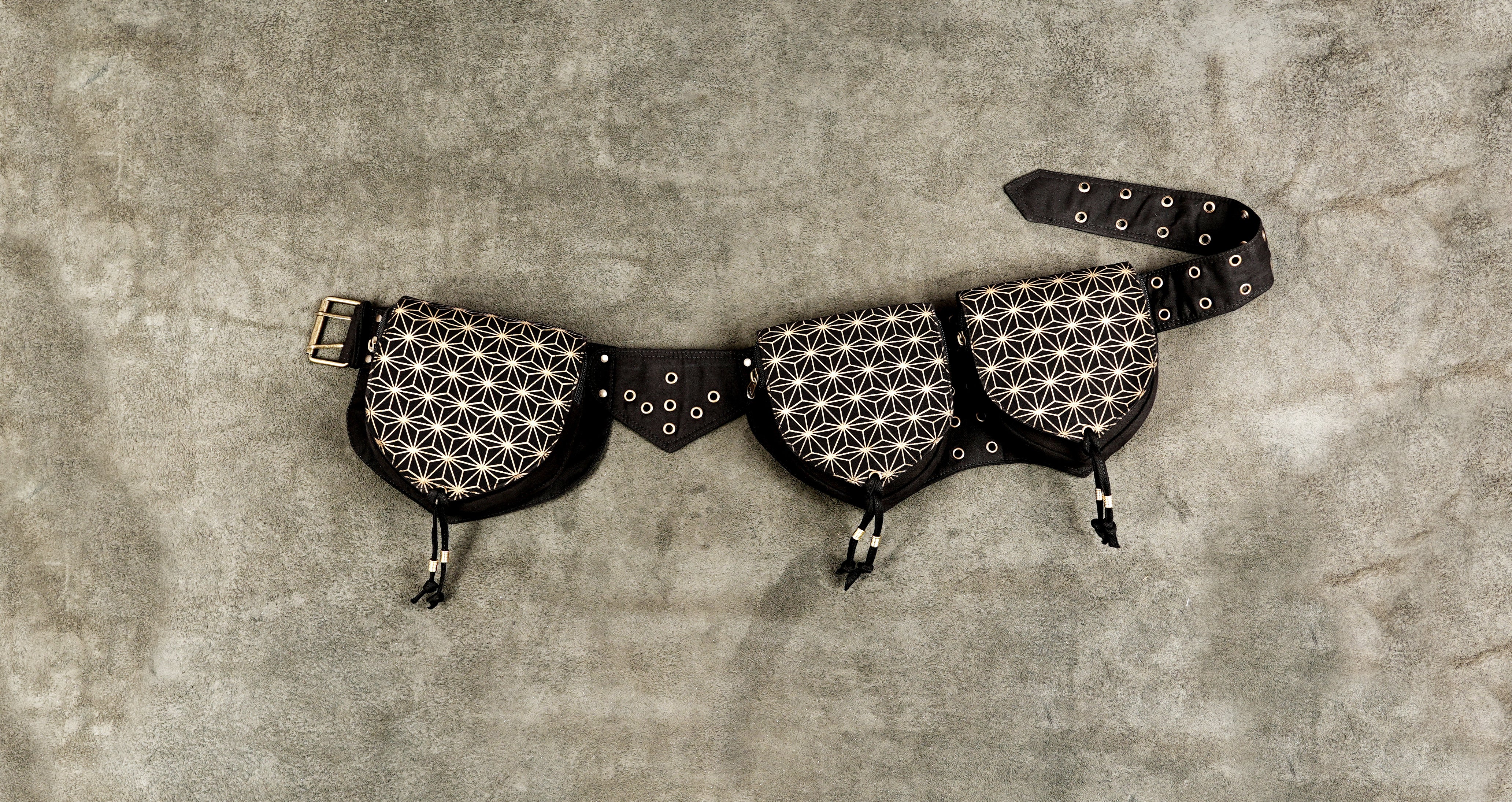 Black canvas festival belt bag with sacred geometry print laid flat on concrete