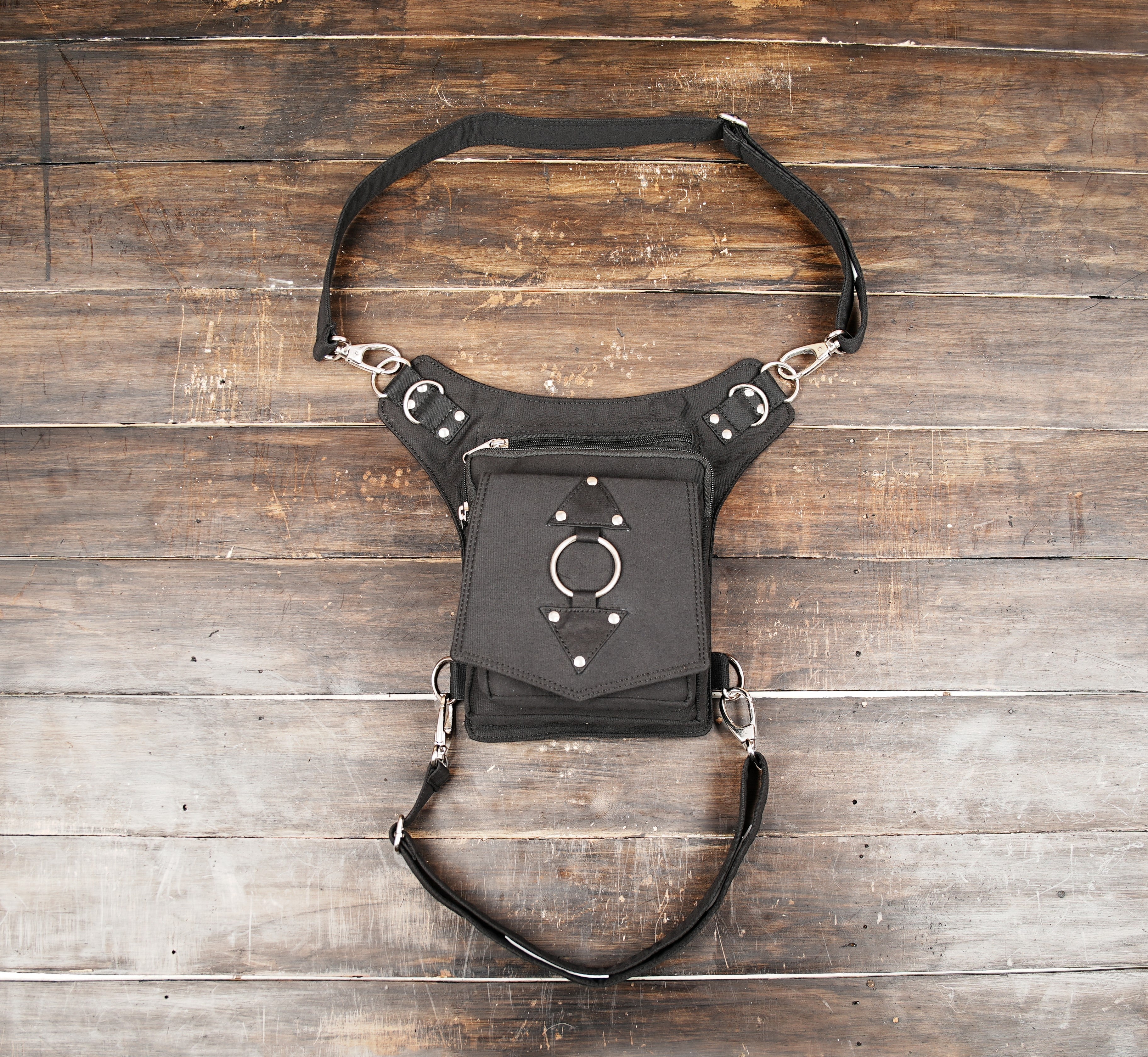 Black cotton waist and thigh bag with adjustable straps on wooden background