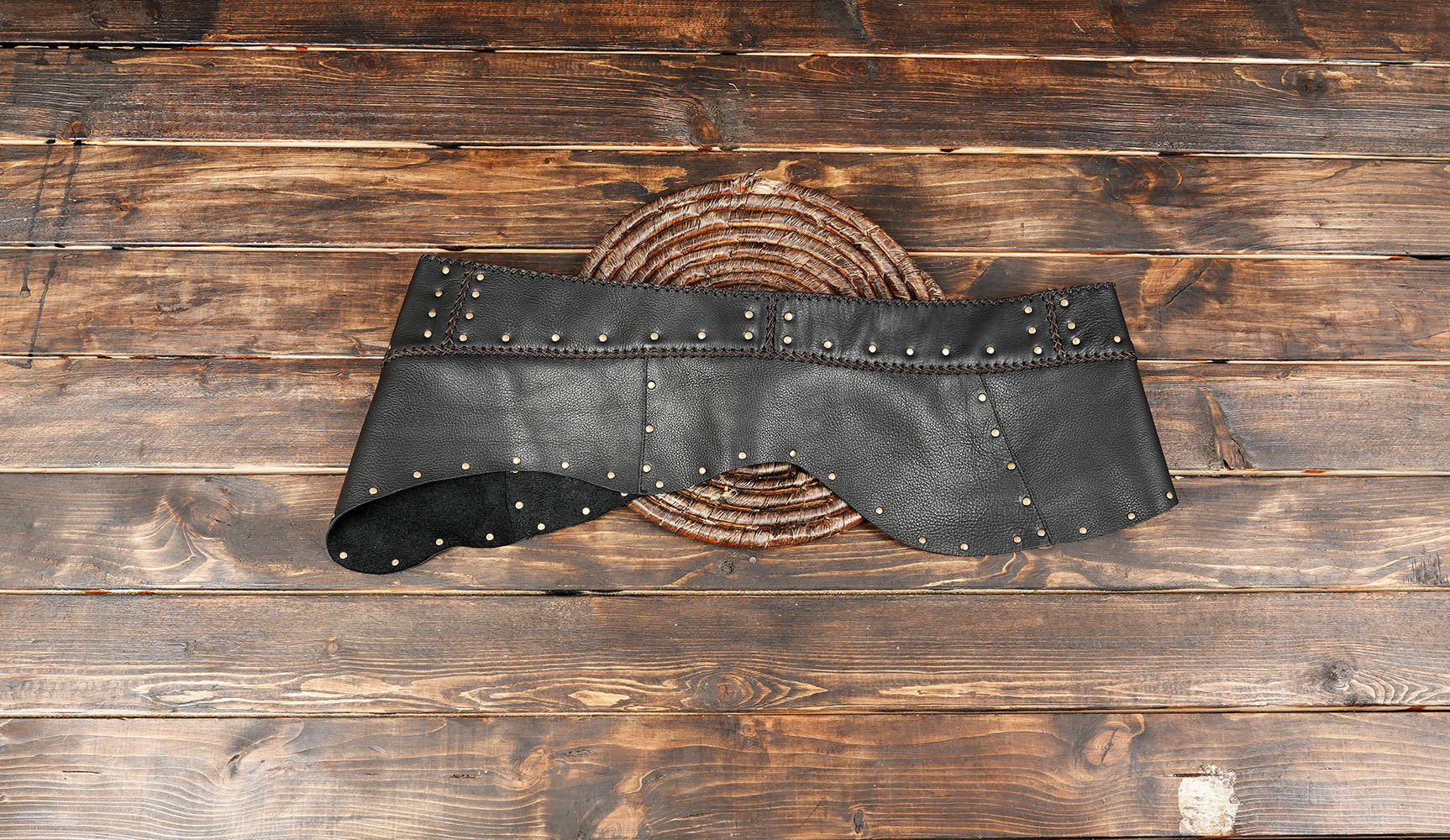 Black leather western skirt with metal stud accents on wooden background