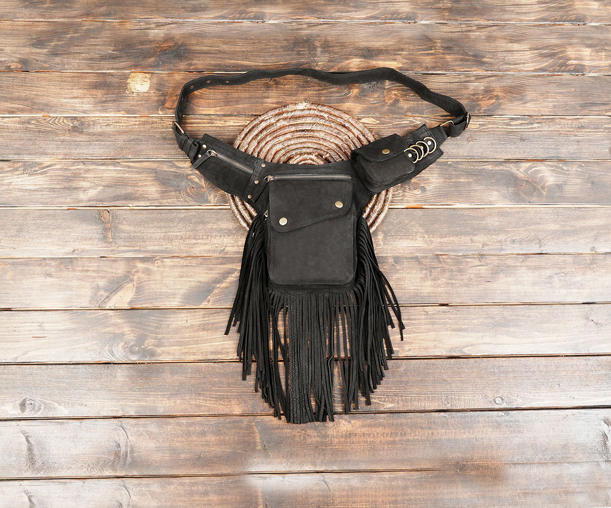 Black cotton fringe waist bag with adjustable belt on wooden background