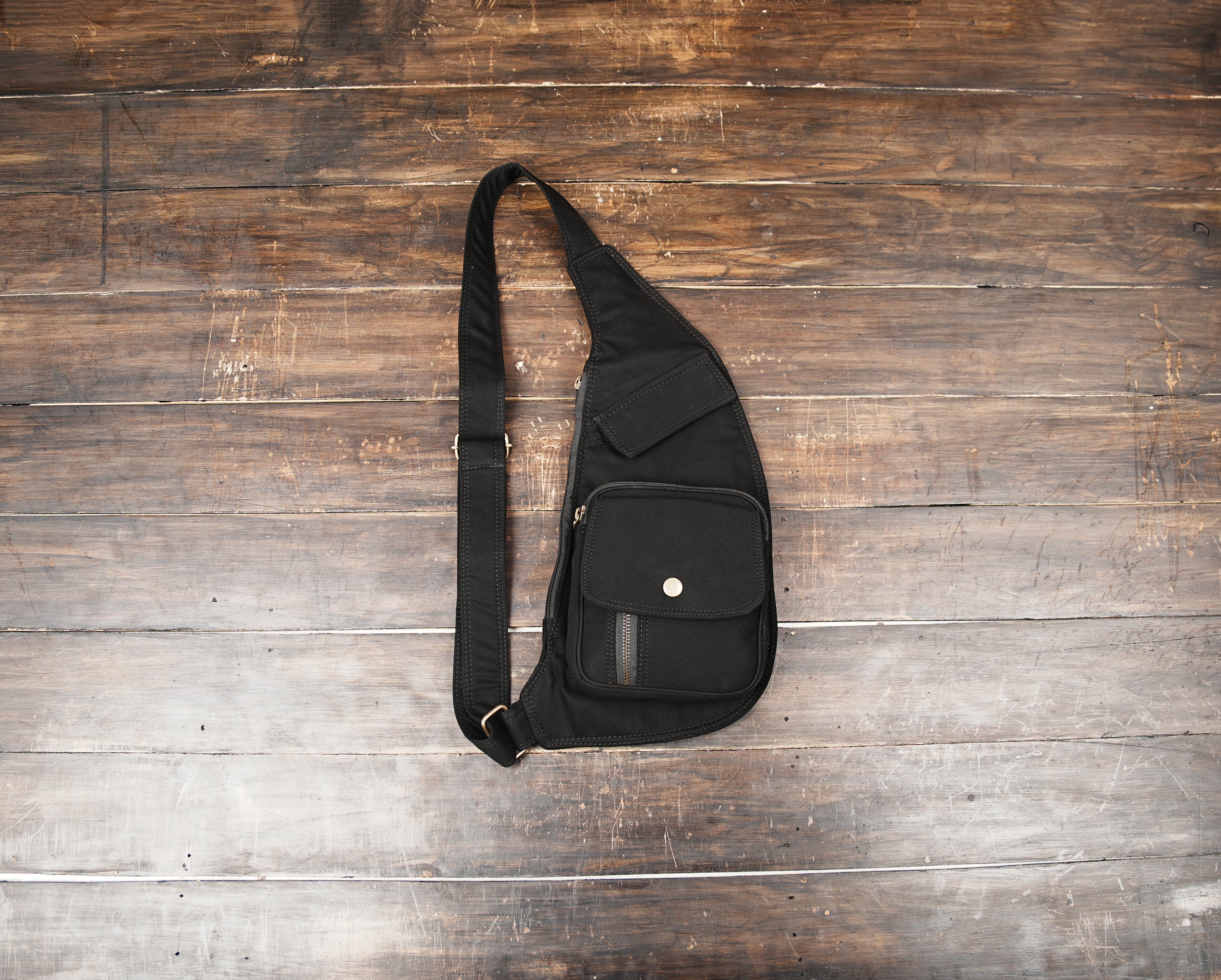 Single strap sling bag featuring front multi-pockets and a snap-button pouch