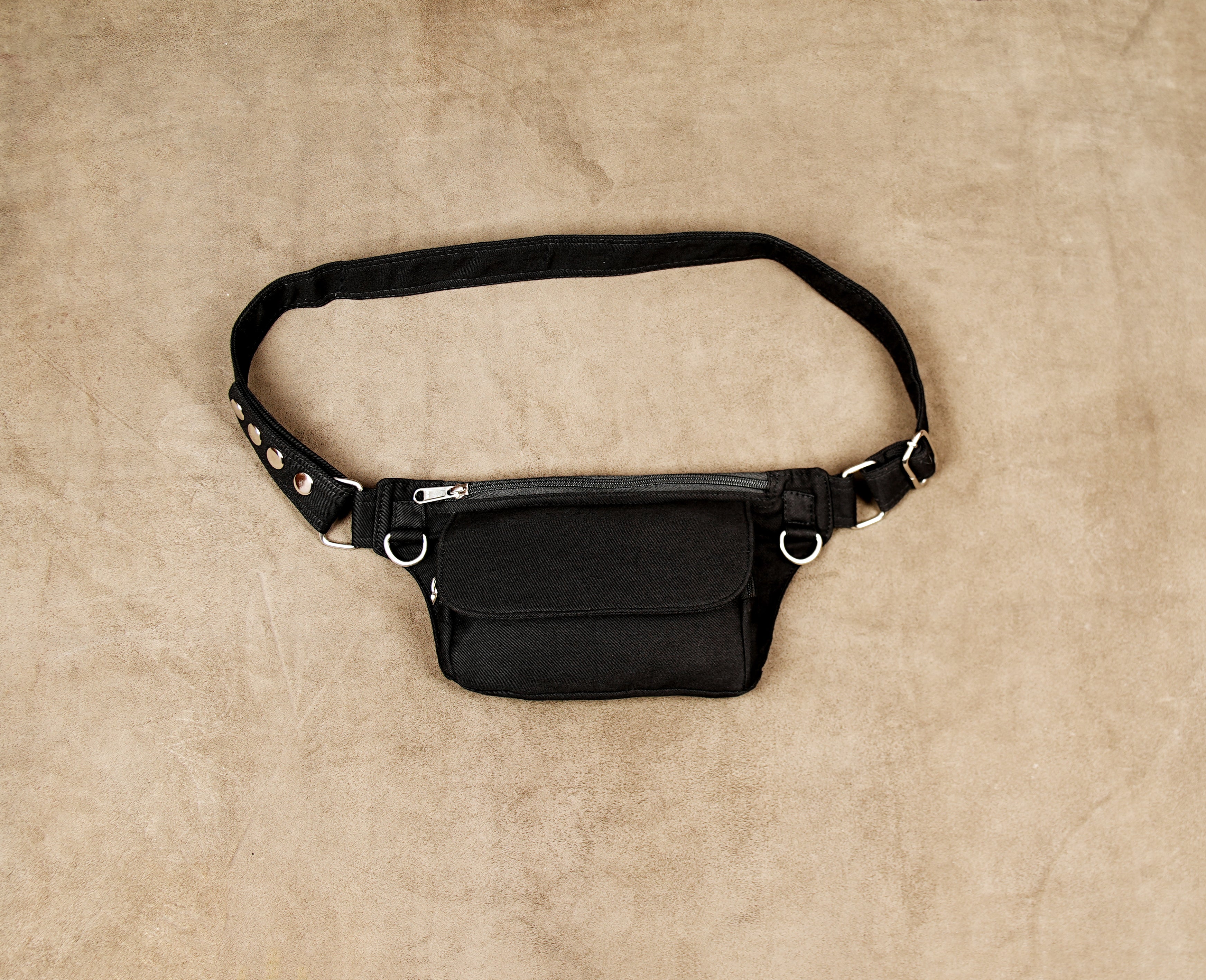 Black cotton canvas waist belt bag with nickel silver hardware and front pocket.