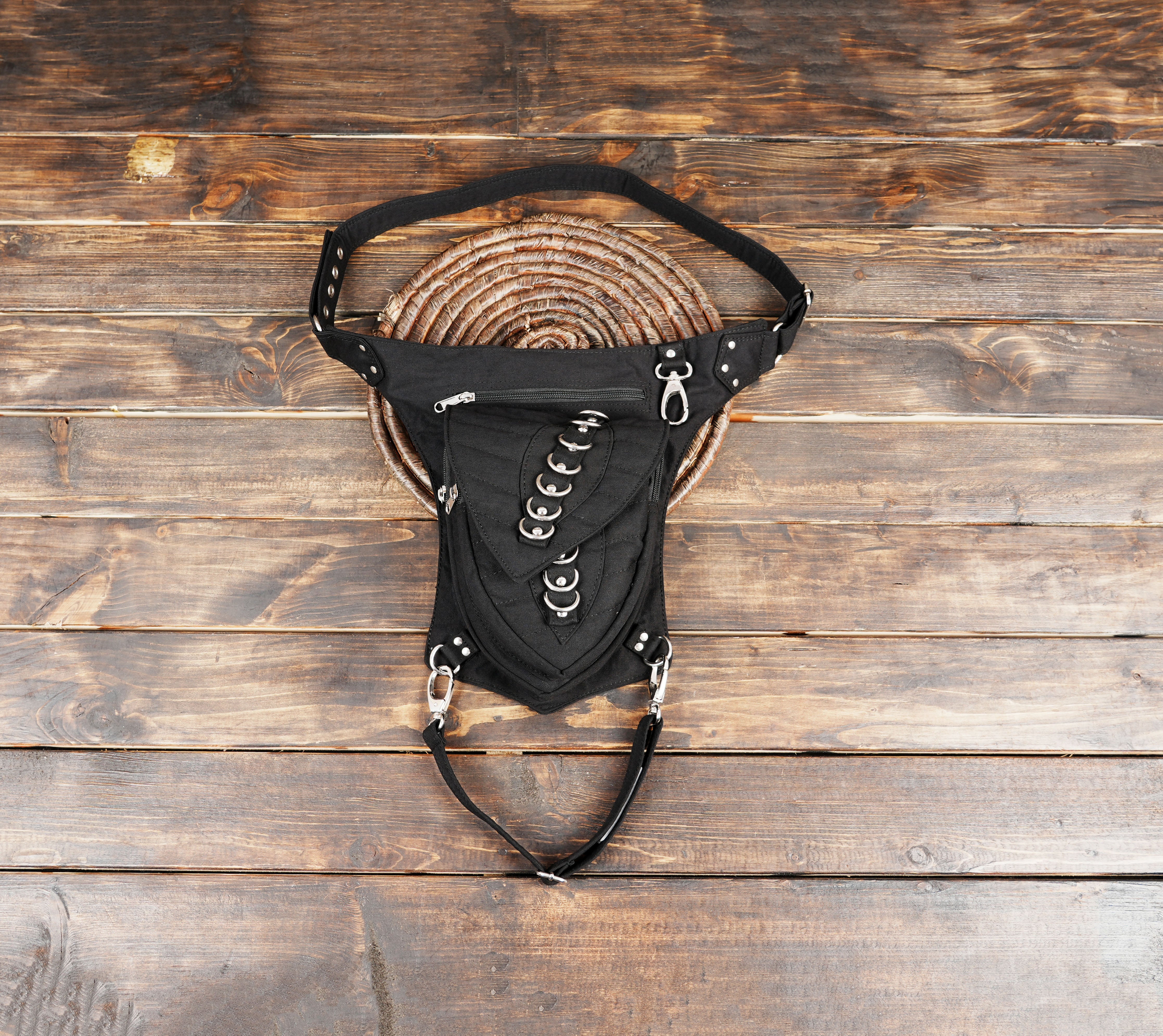 Black cotton waist and thigh bag with D-ring design on wooden background
