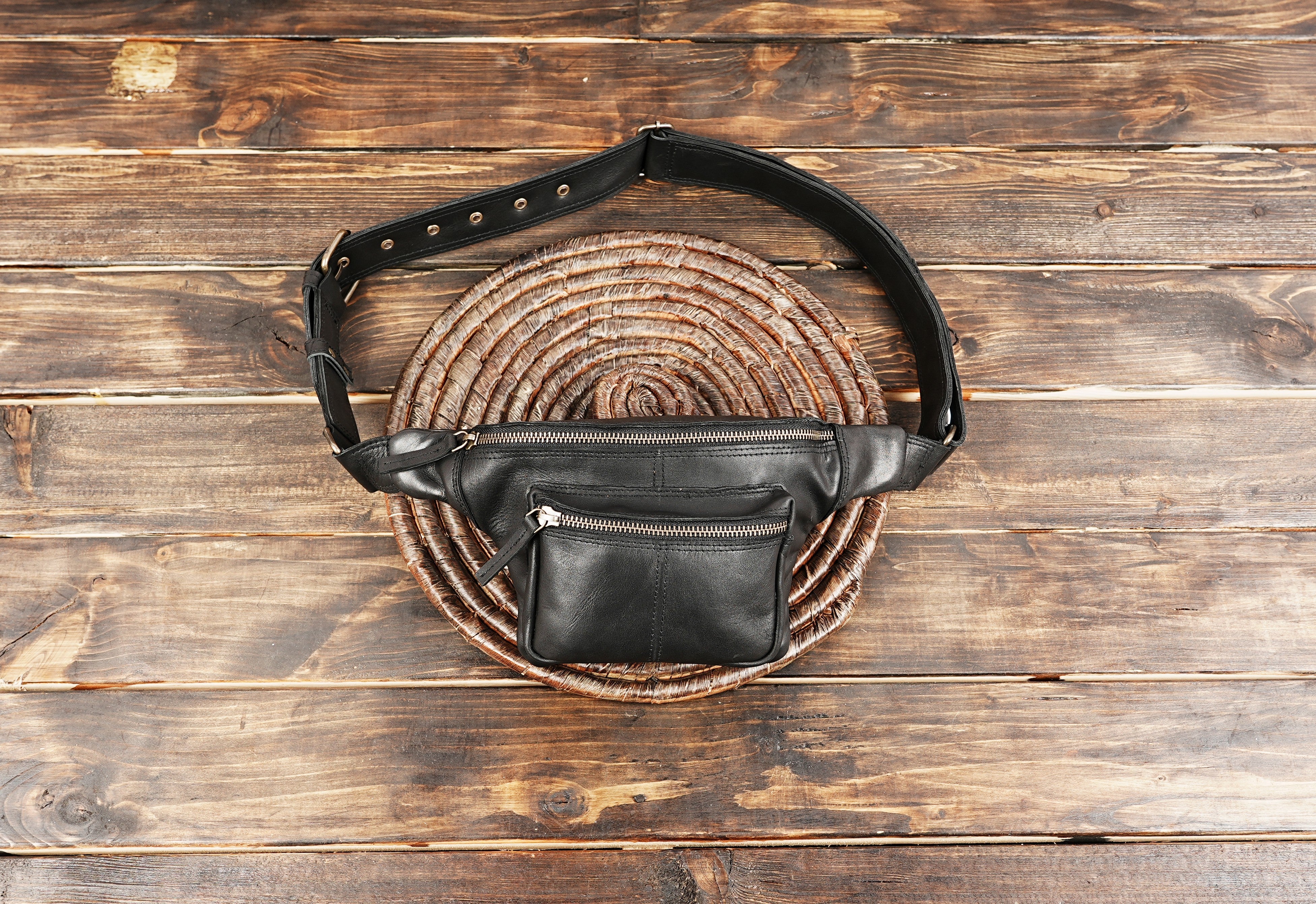Black leather waist bag on wooden background