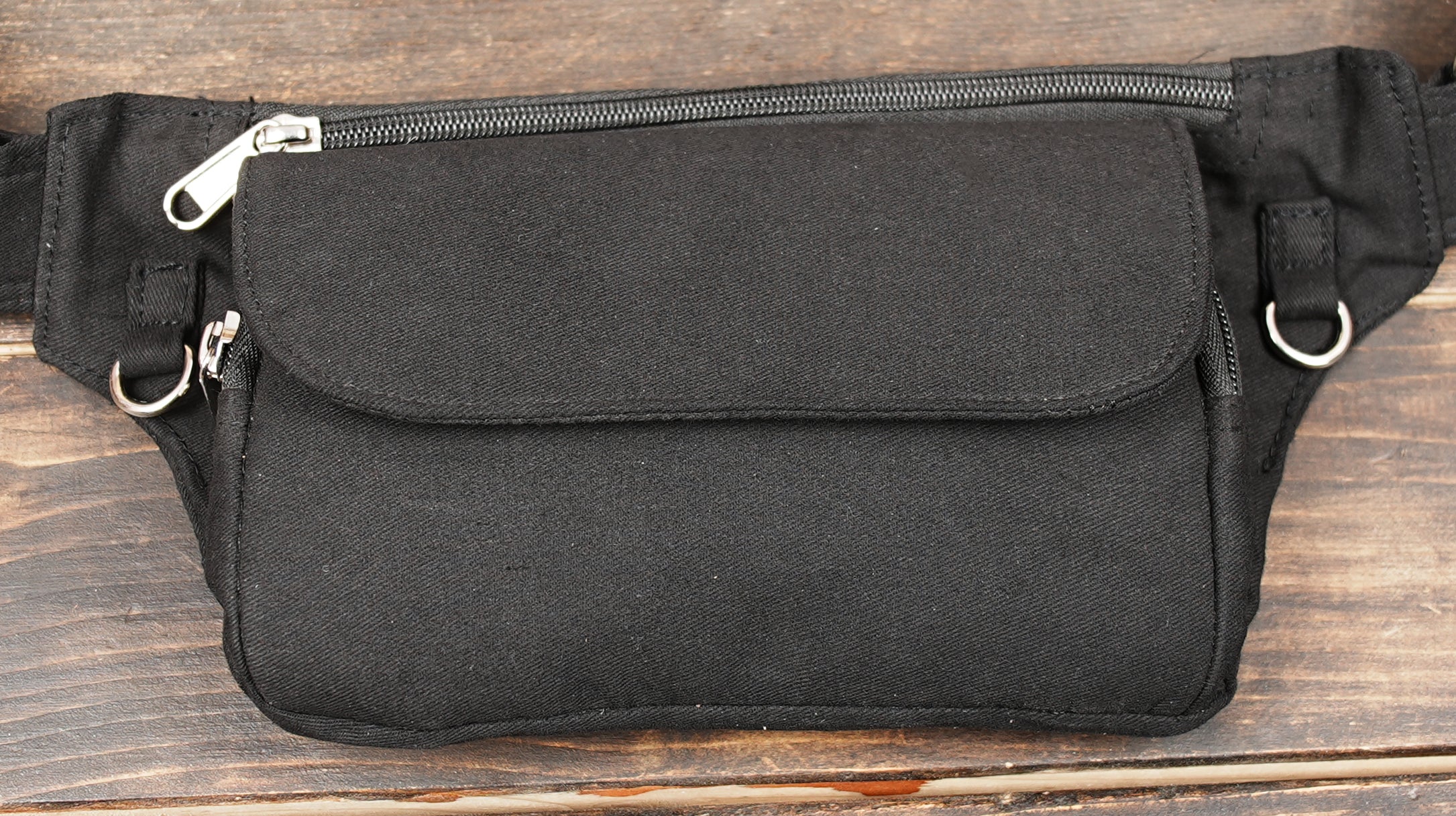 Simple black belt bag with front zip pocket on wooden background