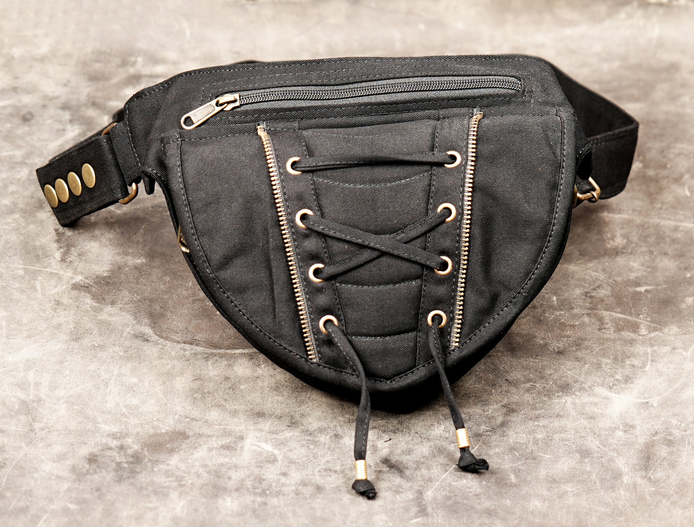 A black canvas hip bag designed for festivals, showing the side release buckle and adjustable strap length, clearly displaying the corset pouch.