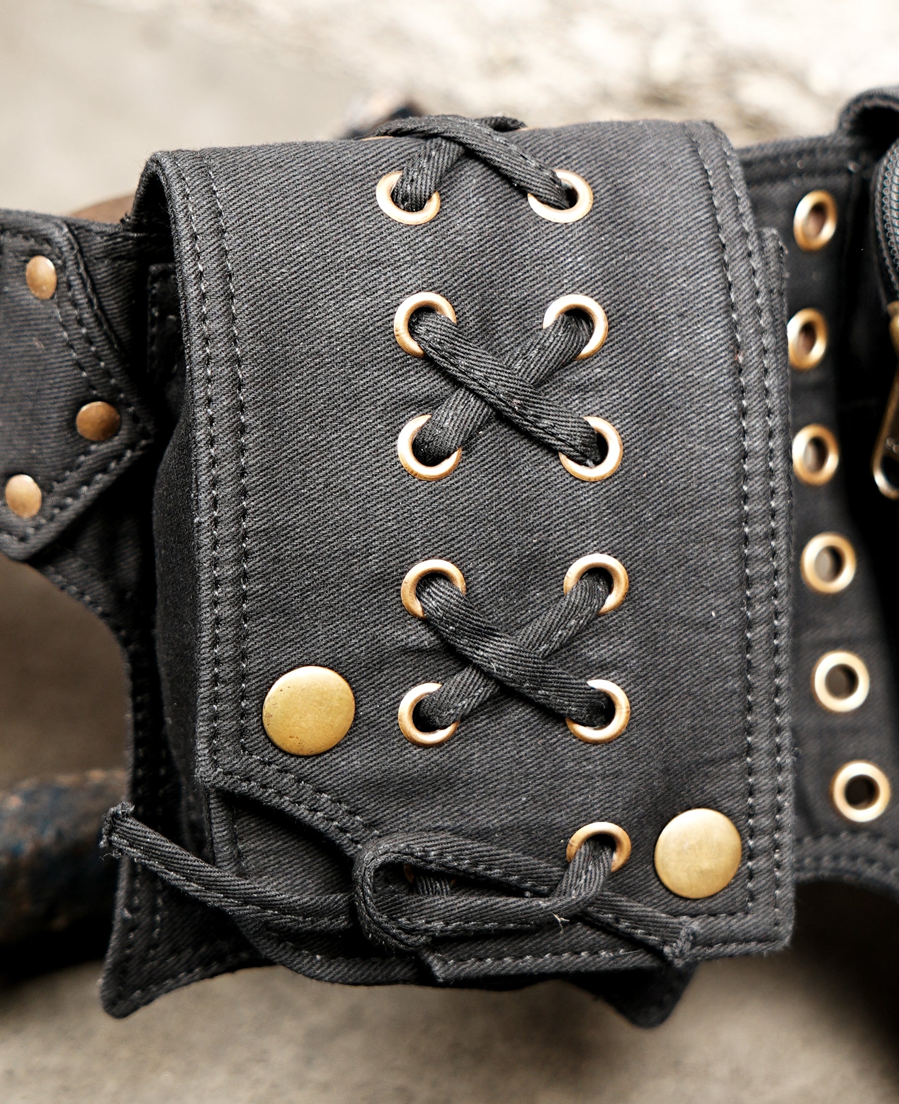 Hands-free black bum bag featuring laced pockets and brass studs