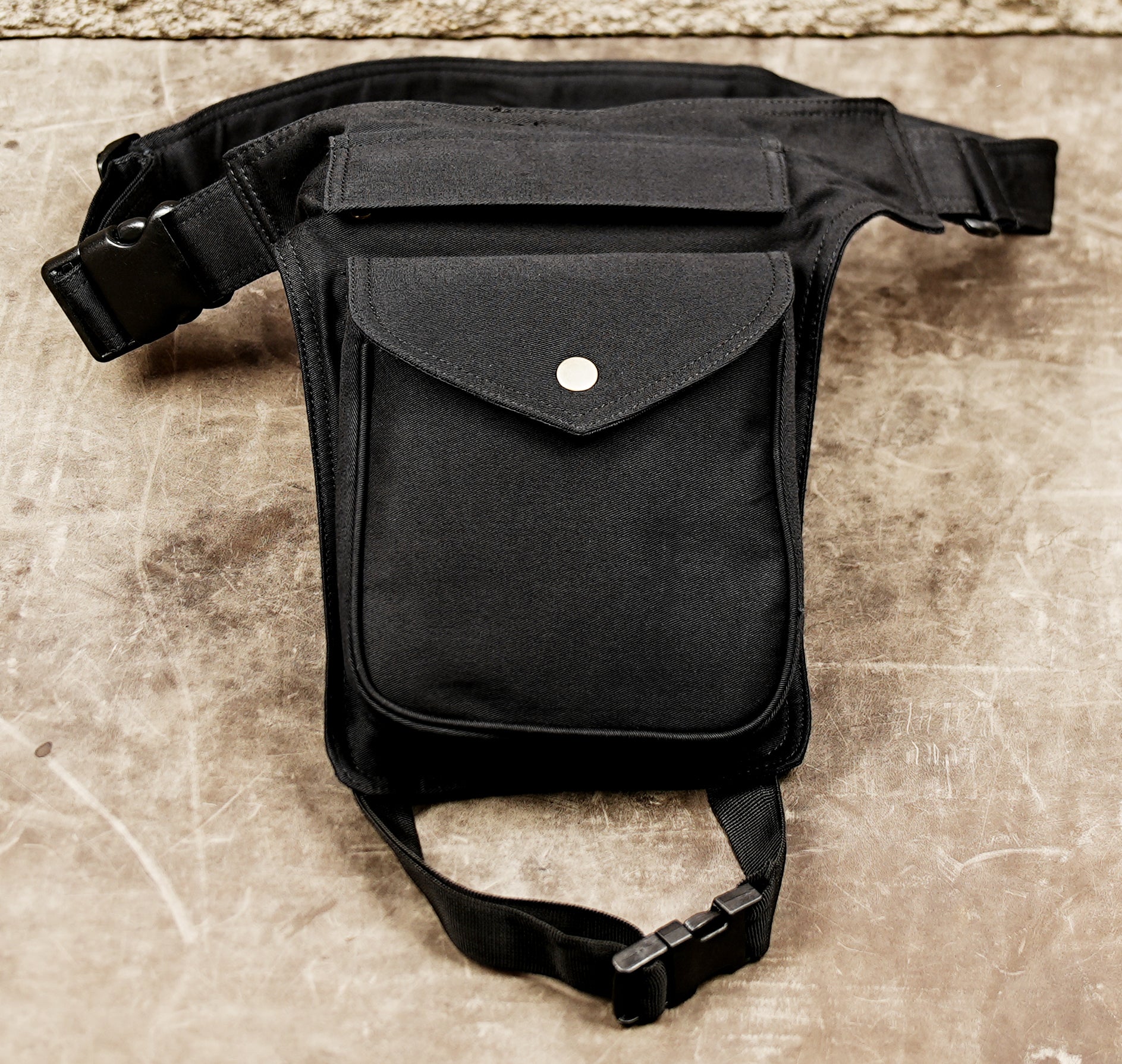 Black burner style hip bag with adjustable waist belt and leg strap.