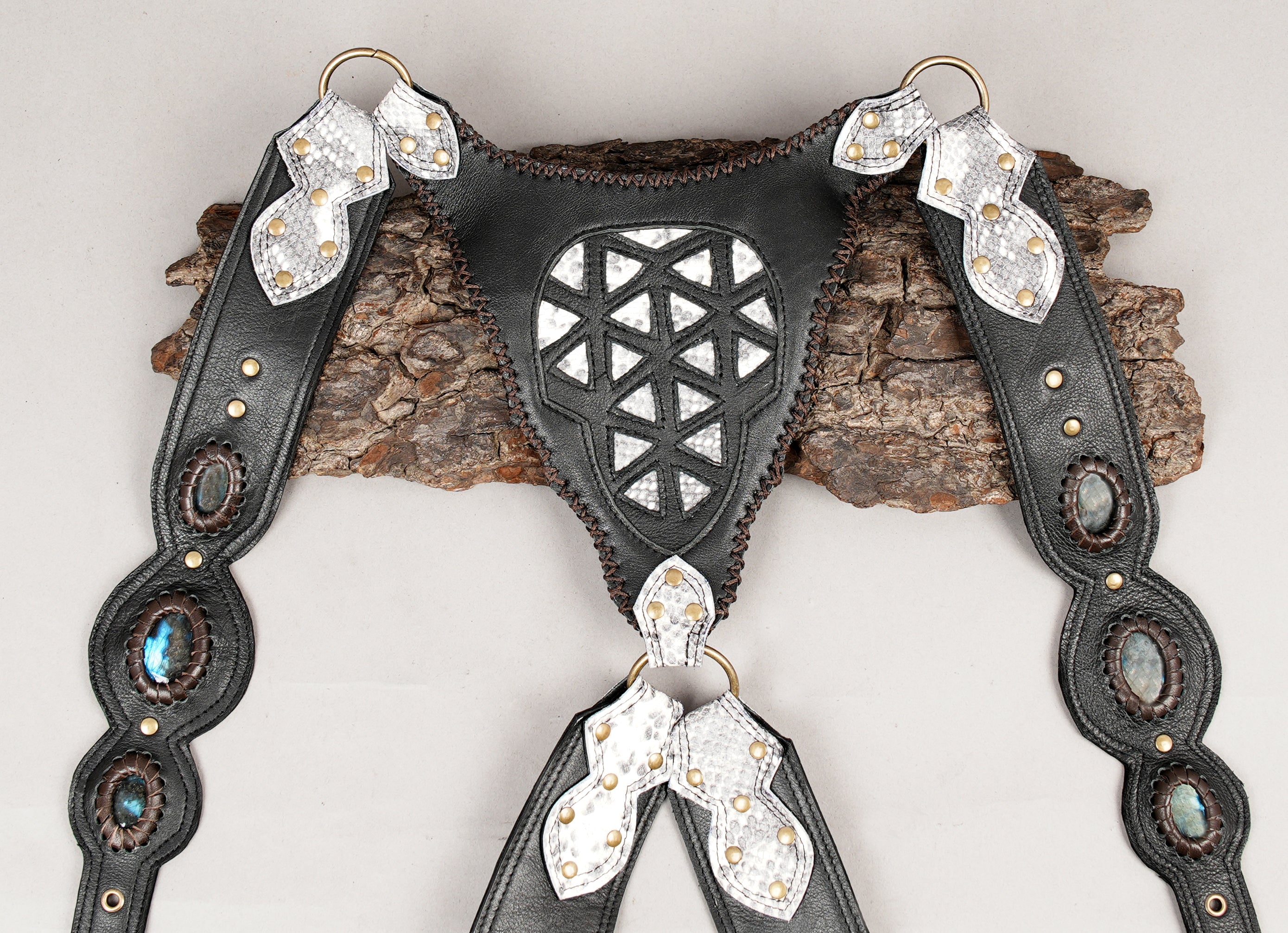 Black leather shoulder holster with silver textured flaps and braided edges