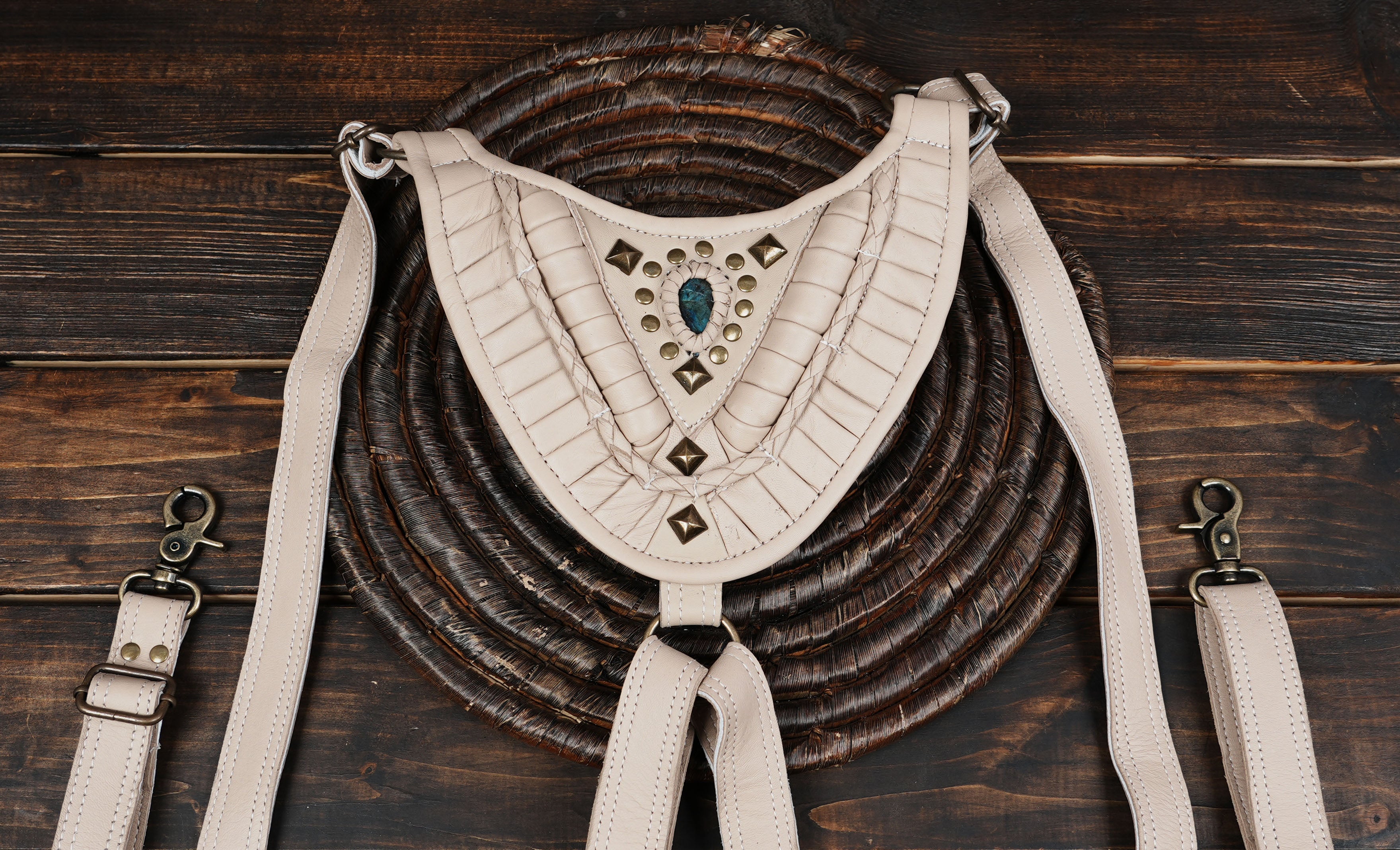 “Artisan ivory leather holster featuring tribal patterns and gemstone centerpiece”
