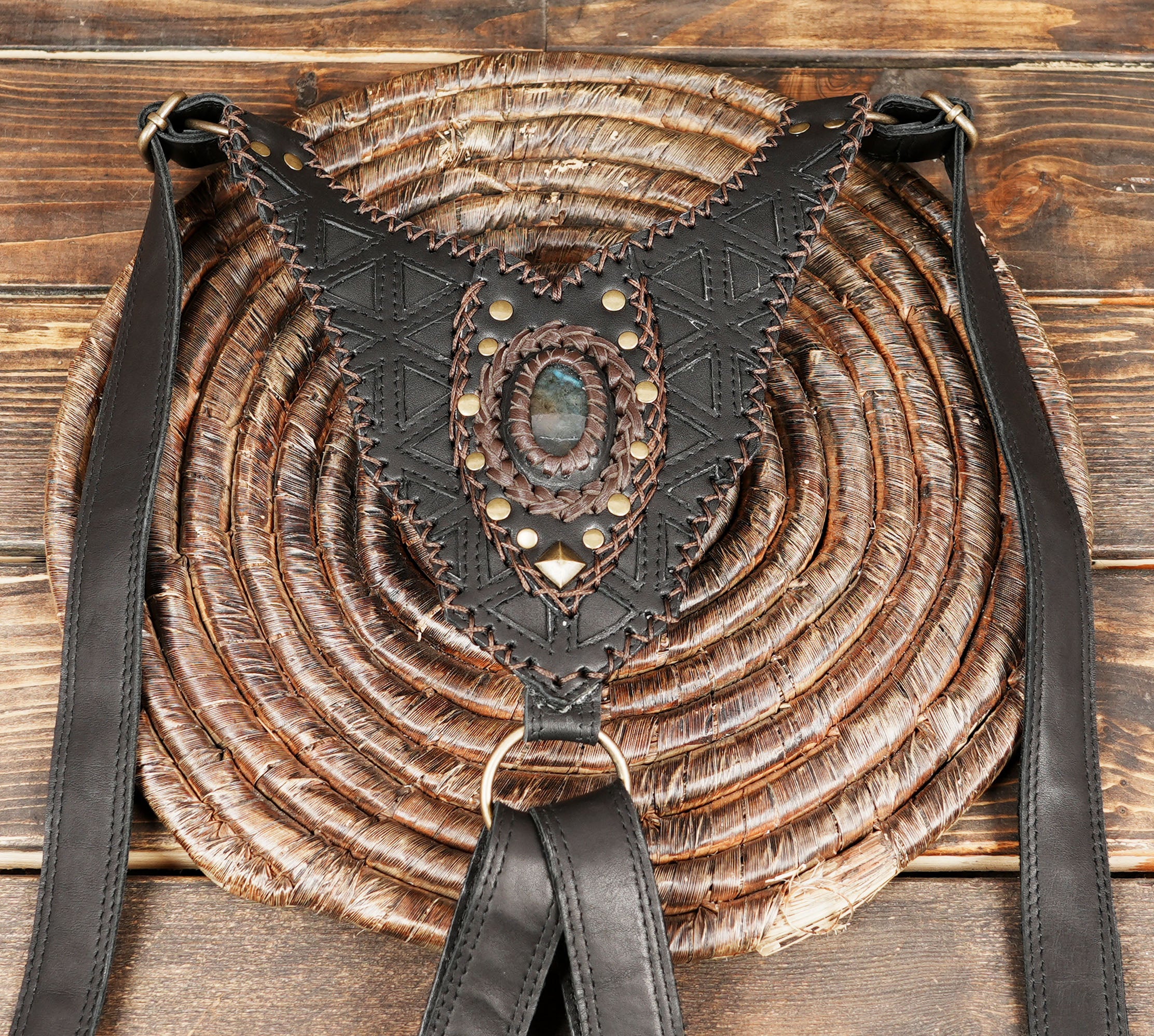 “Black leather festival holster with braided edges and decorative gemstone centerpiece”
