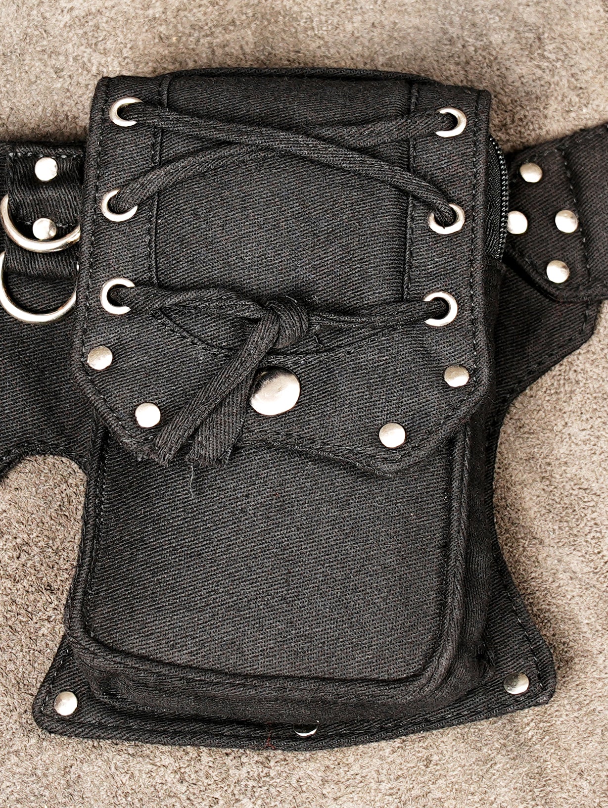 Adjustable canvas waist belt bag featuring detailed lacing, silver metal studs, and functional D-rings.