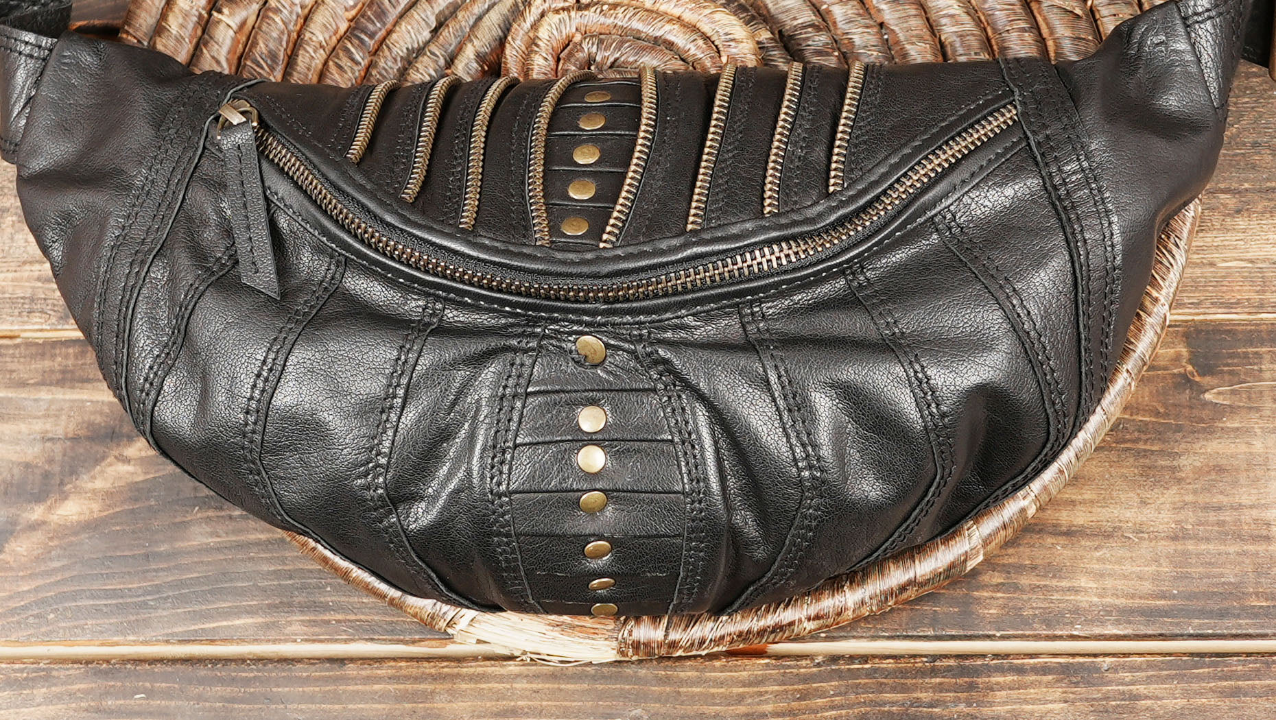 Black leather belt bag with antique brass hardware and stitched detailing.