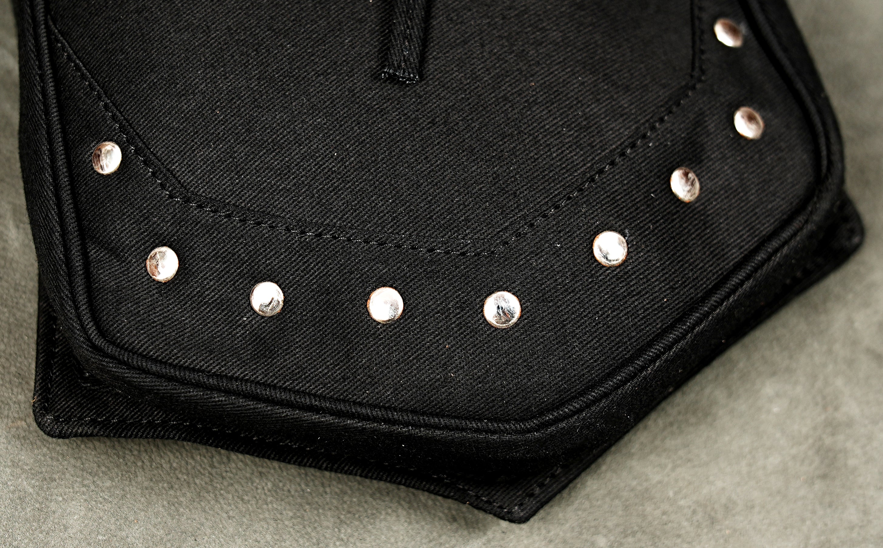 Black cotton festival belt bag with two utility pouches metal eyelets and decorative stud details.