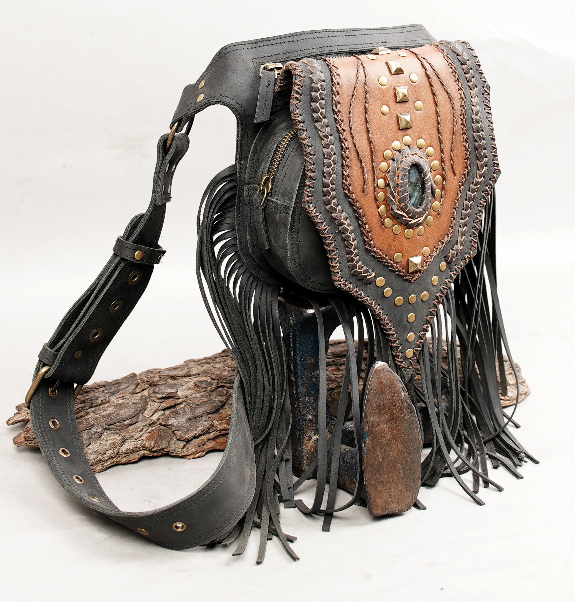 Steampunk-inspired leather waist bag with gemstone and layered stitching.