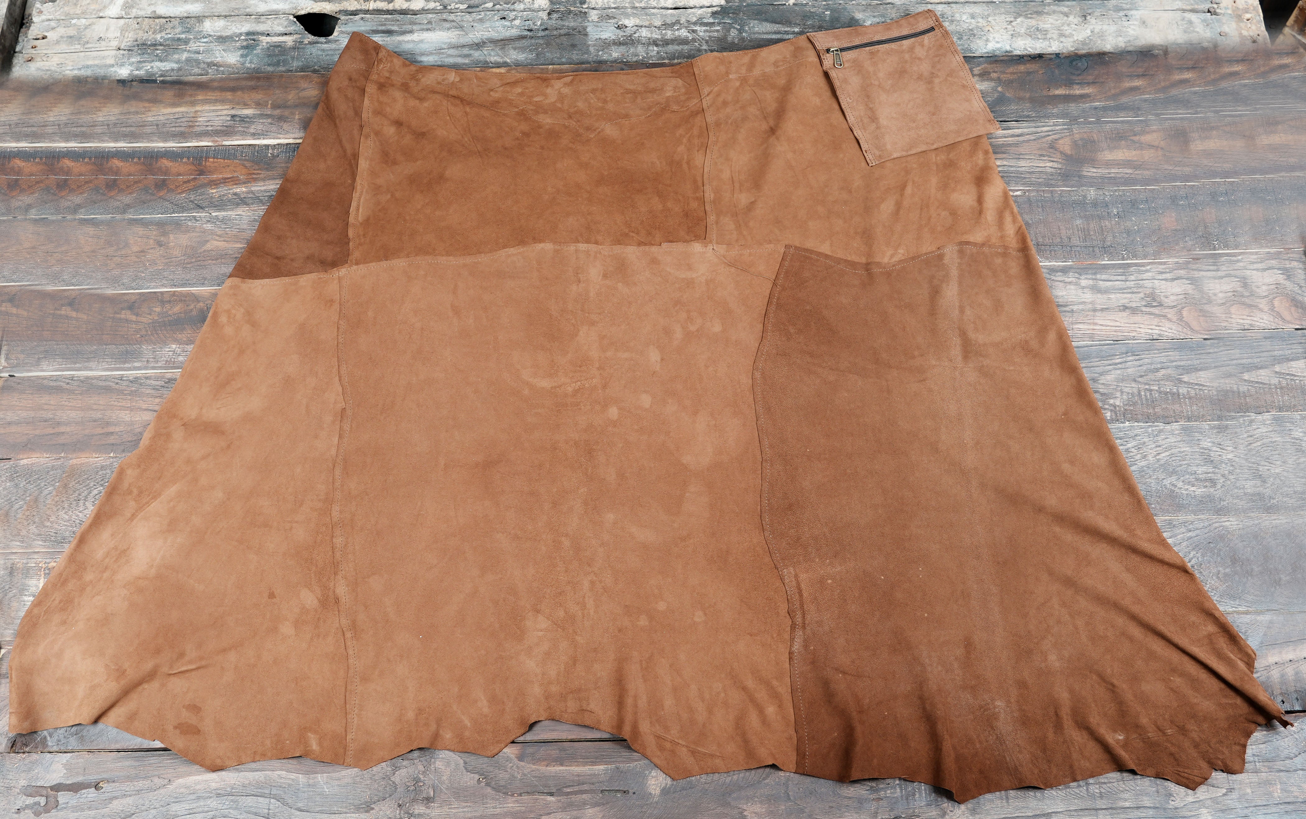 Handmade brown suede skirt displayed on rustic wooden planks