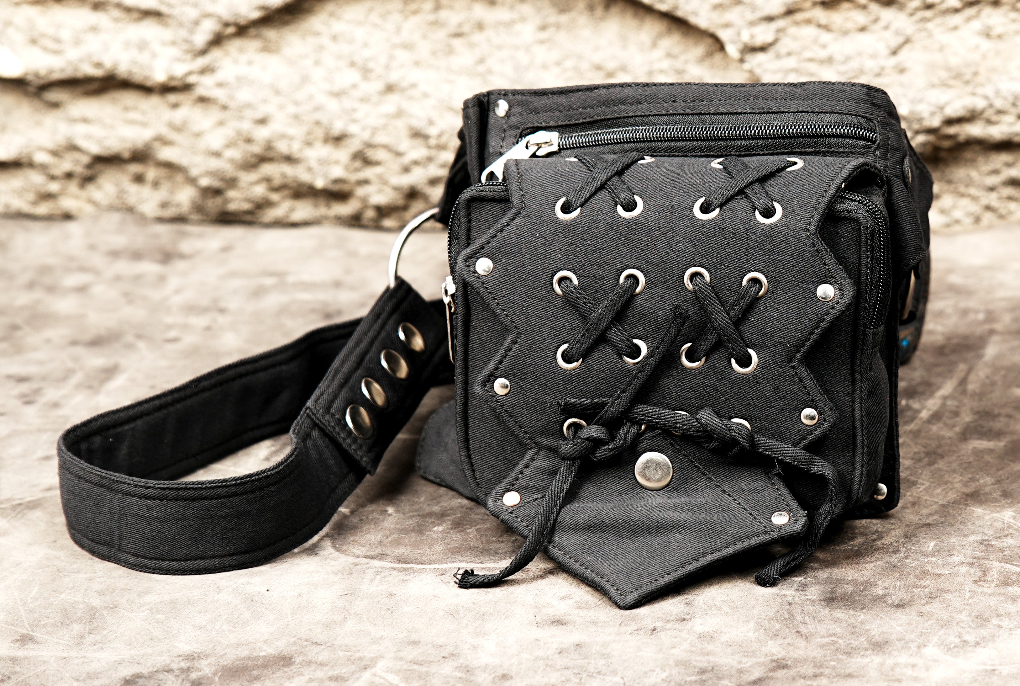 Urban style fanny pack, black cotton with polished metal eyelets, close-up photo.