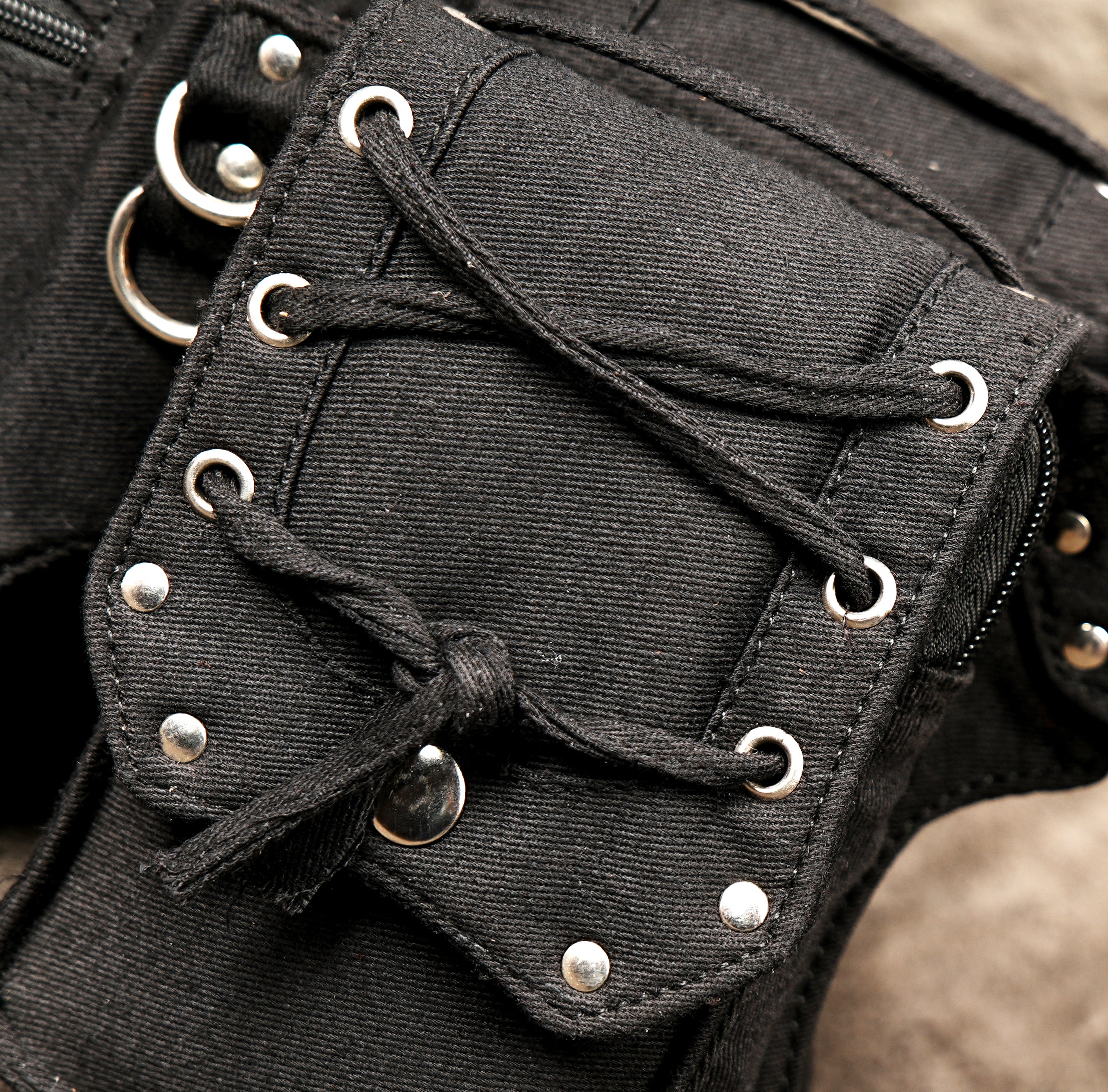 Detailed shot of a utilitarian hip pouch with a robust metal buckle and grommeted adjustment holes.