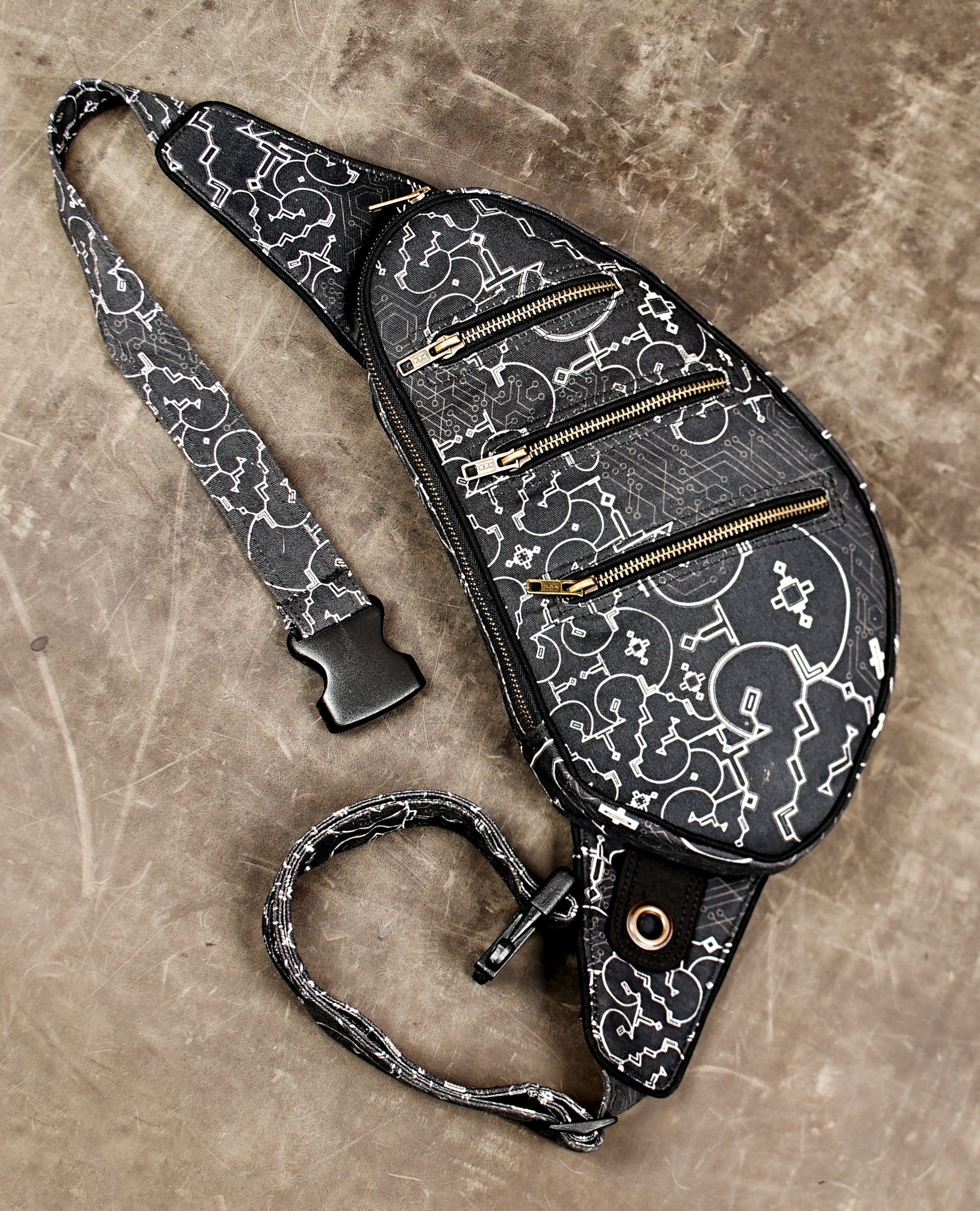 Sci-fi inspired sling bag with three brass zippers and buckle strap