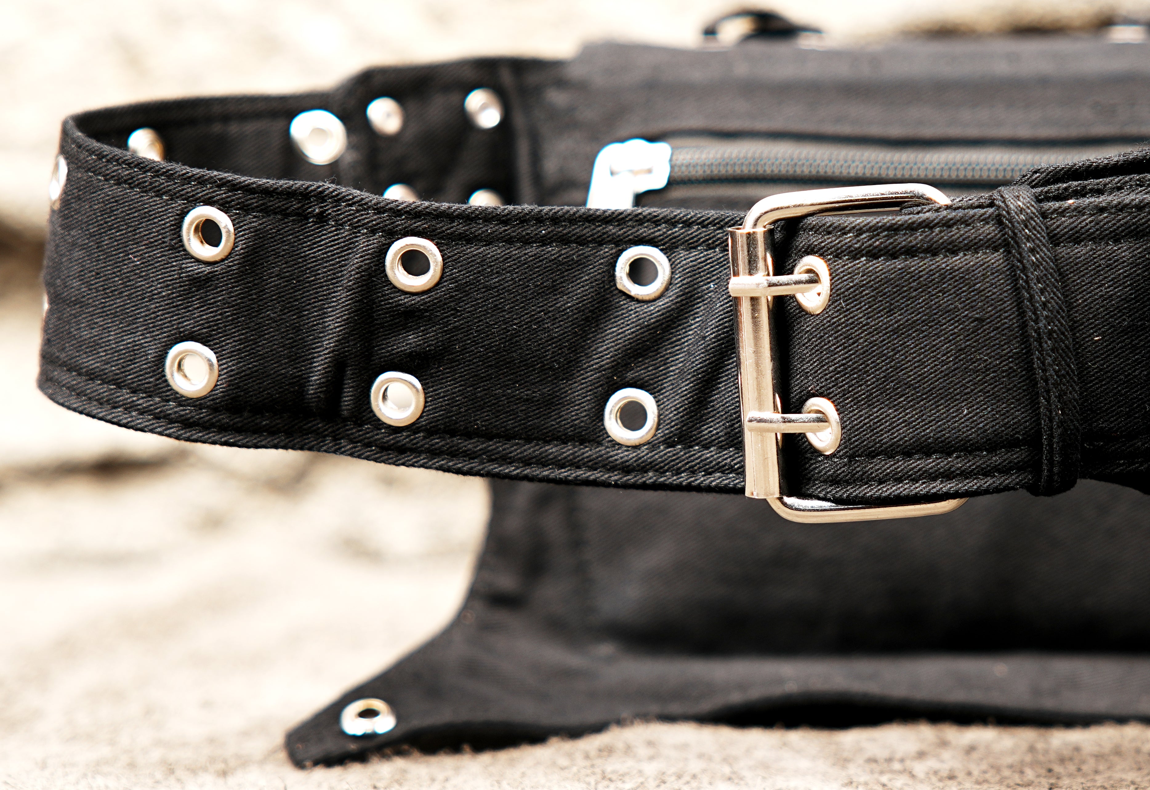 Leather-style black hip bag with attached studded waist strap and eyelet detail.