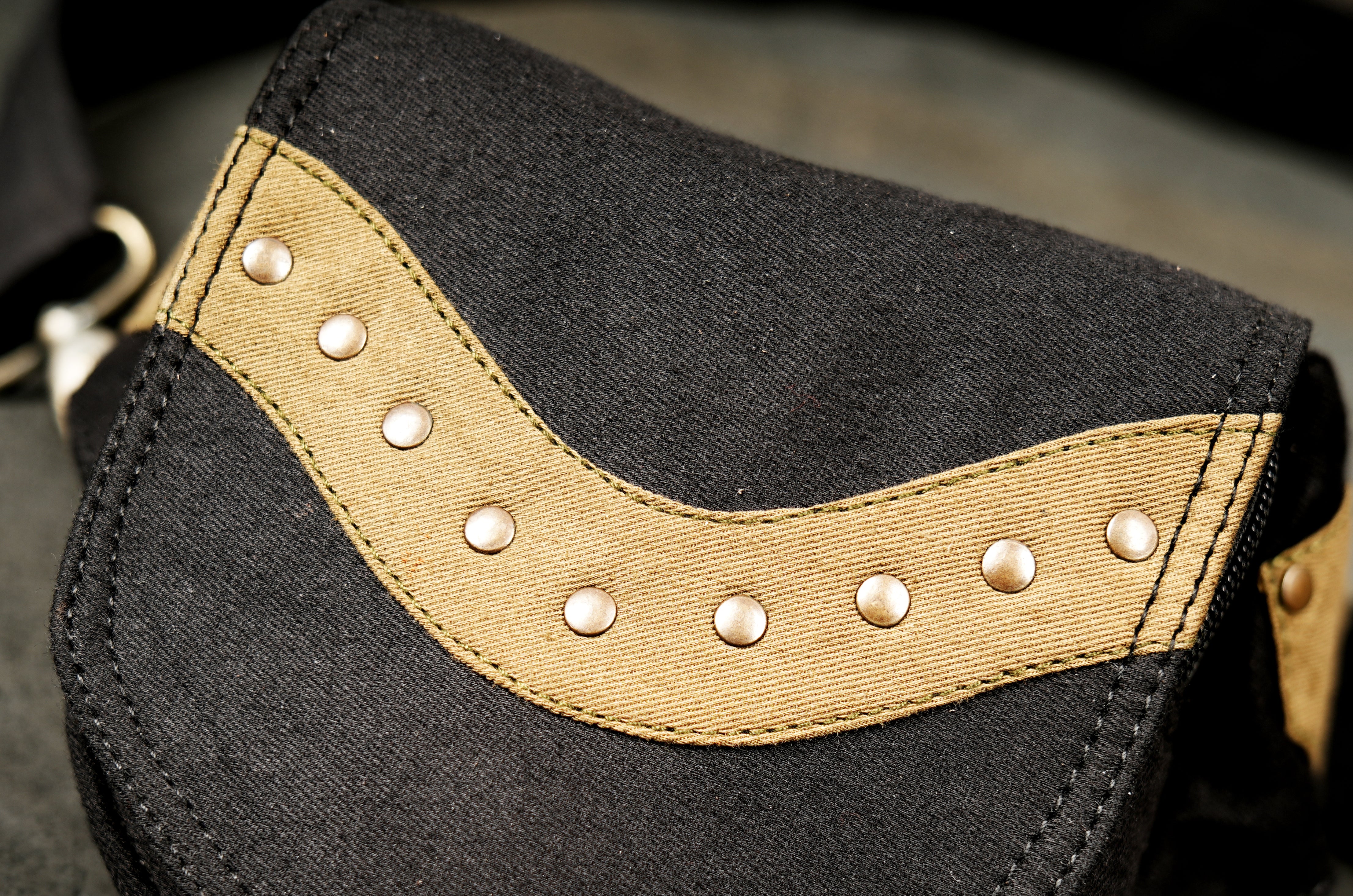 Utilitarian-style hip bag made of sturdy black cotton canvas with contrasting light leather or fabric trim and studs.