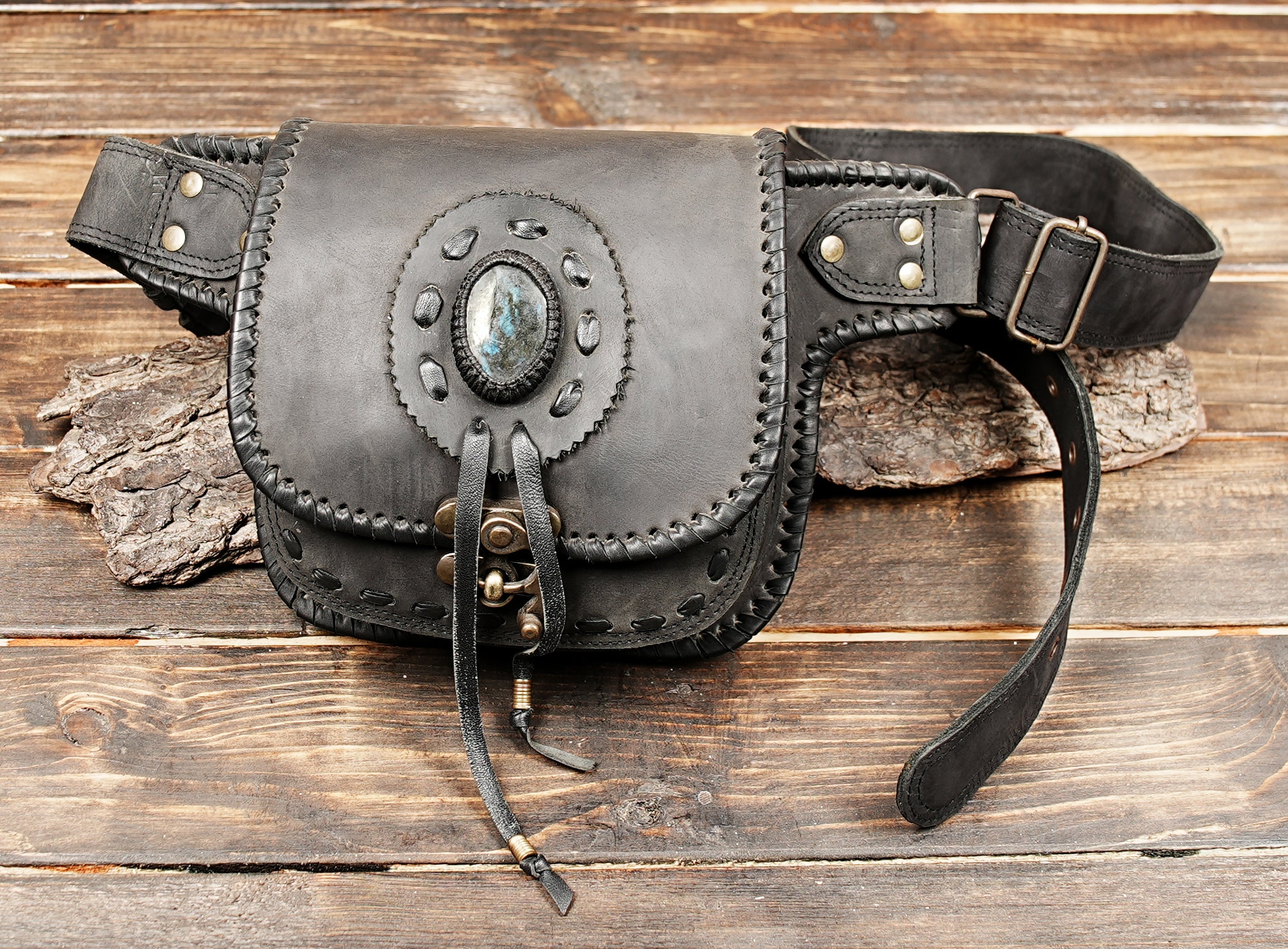 Black leather waist bag laid flat on wooden background