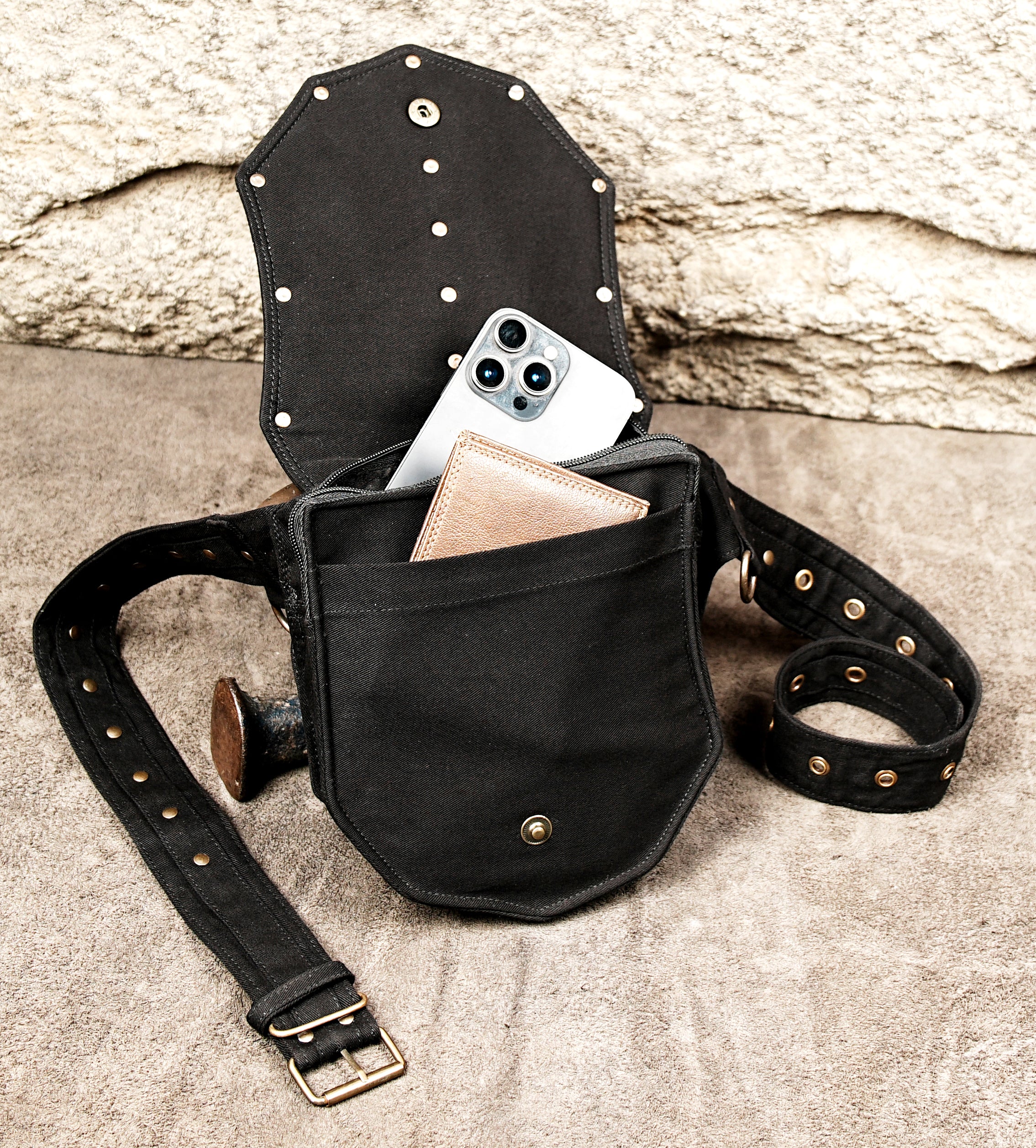 Detail shot of matte black canvas fanny pack worn on the hip, featuring a secure zipper, adjustable strap, and aged brass hardware accents.