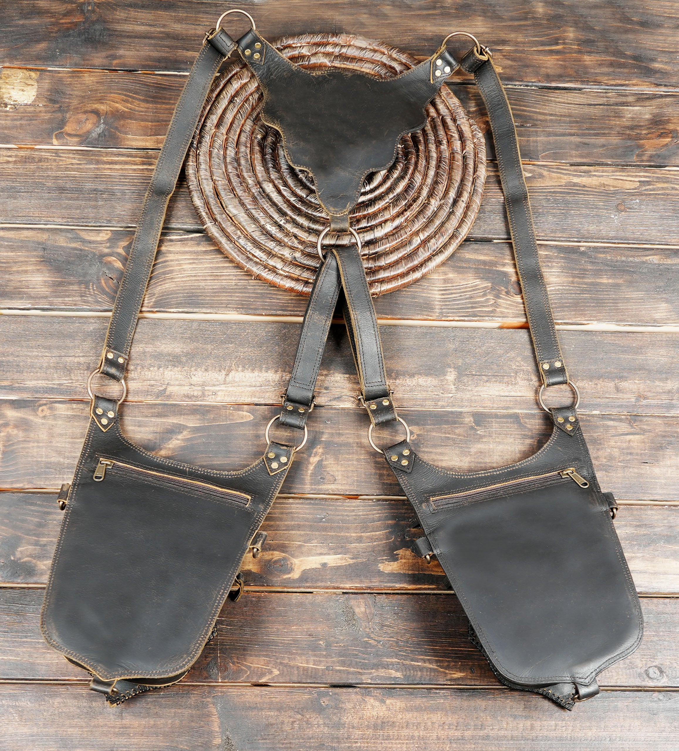 Black leather shoulder bag with straps on a wooden surface