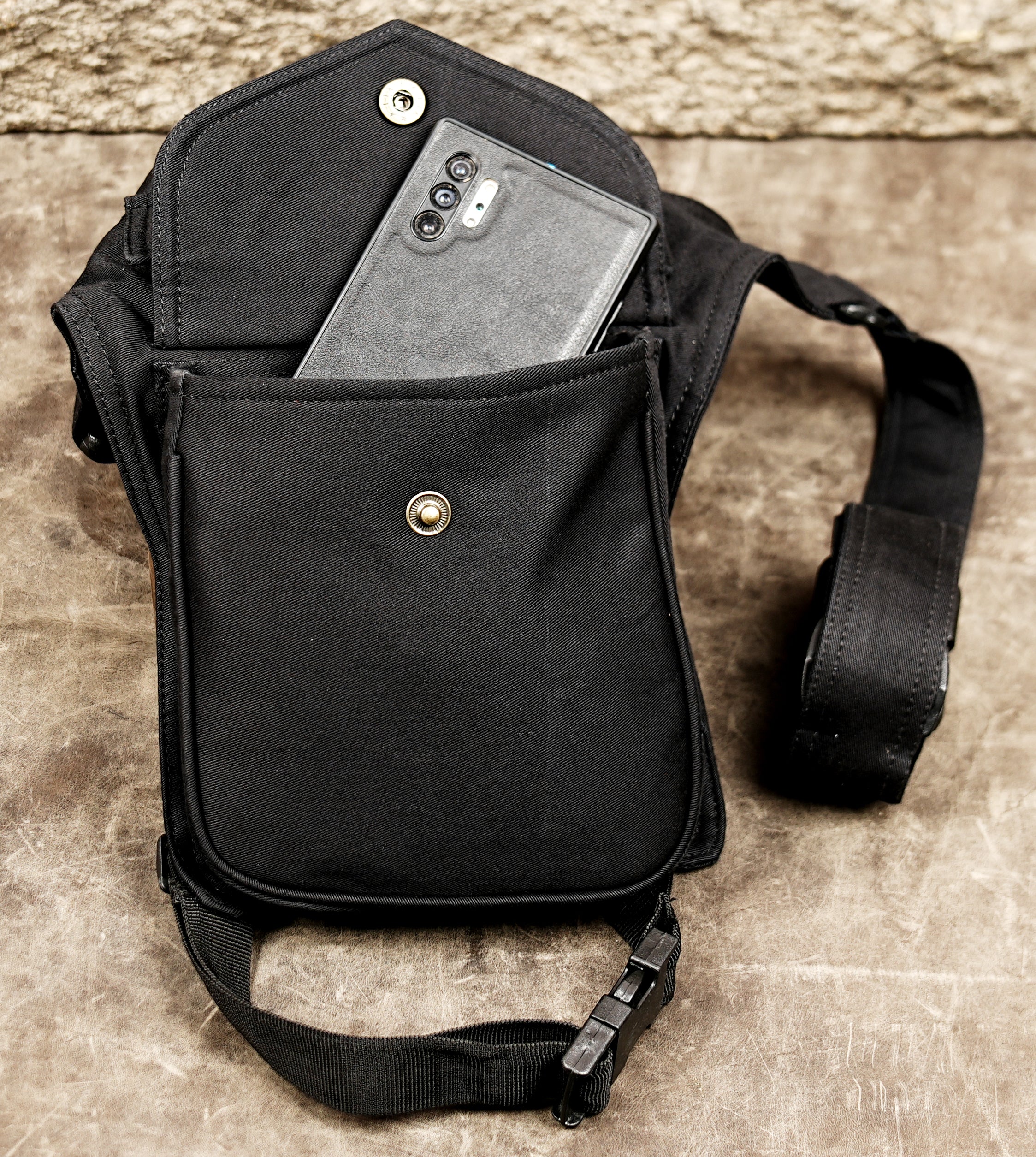 Black travel waist bag with leg strap for hands-free carrying.
