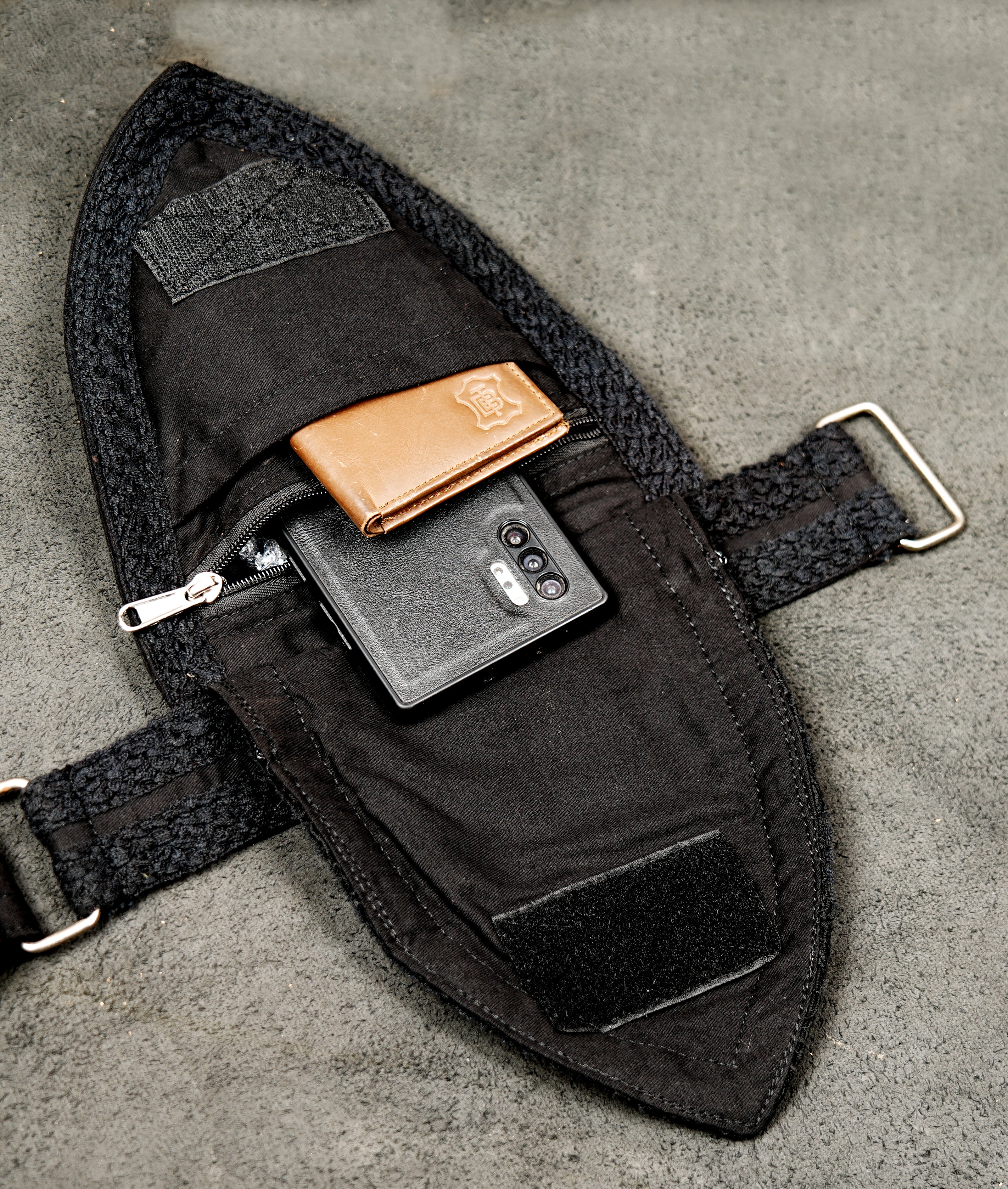 Women's black rave utility belt pouch laid flat on concrete background