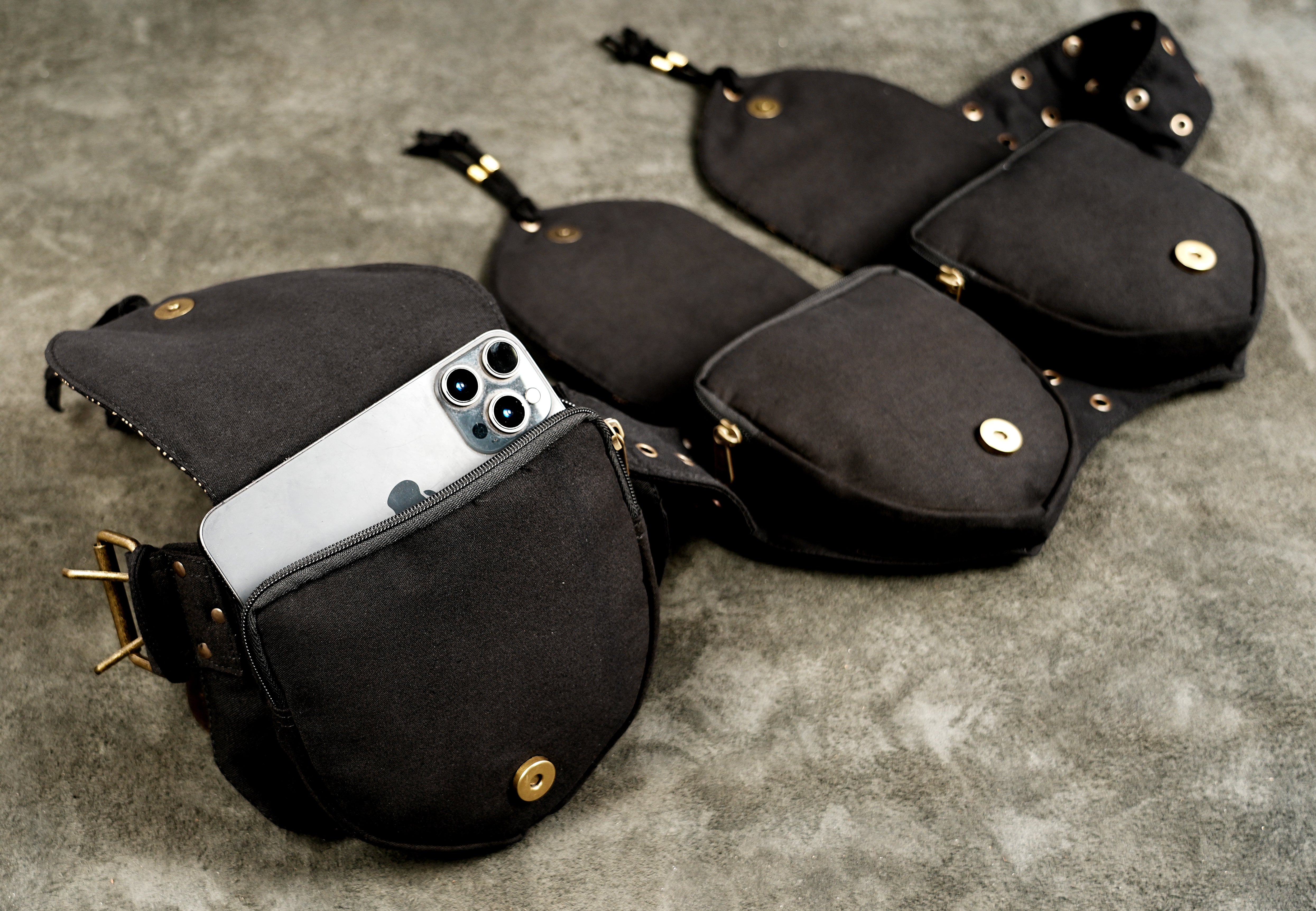 Black utility belt bag flat lay showing buckle, pouches, and stitching detail