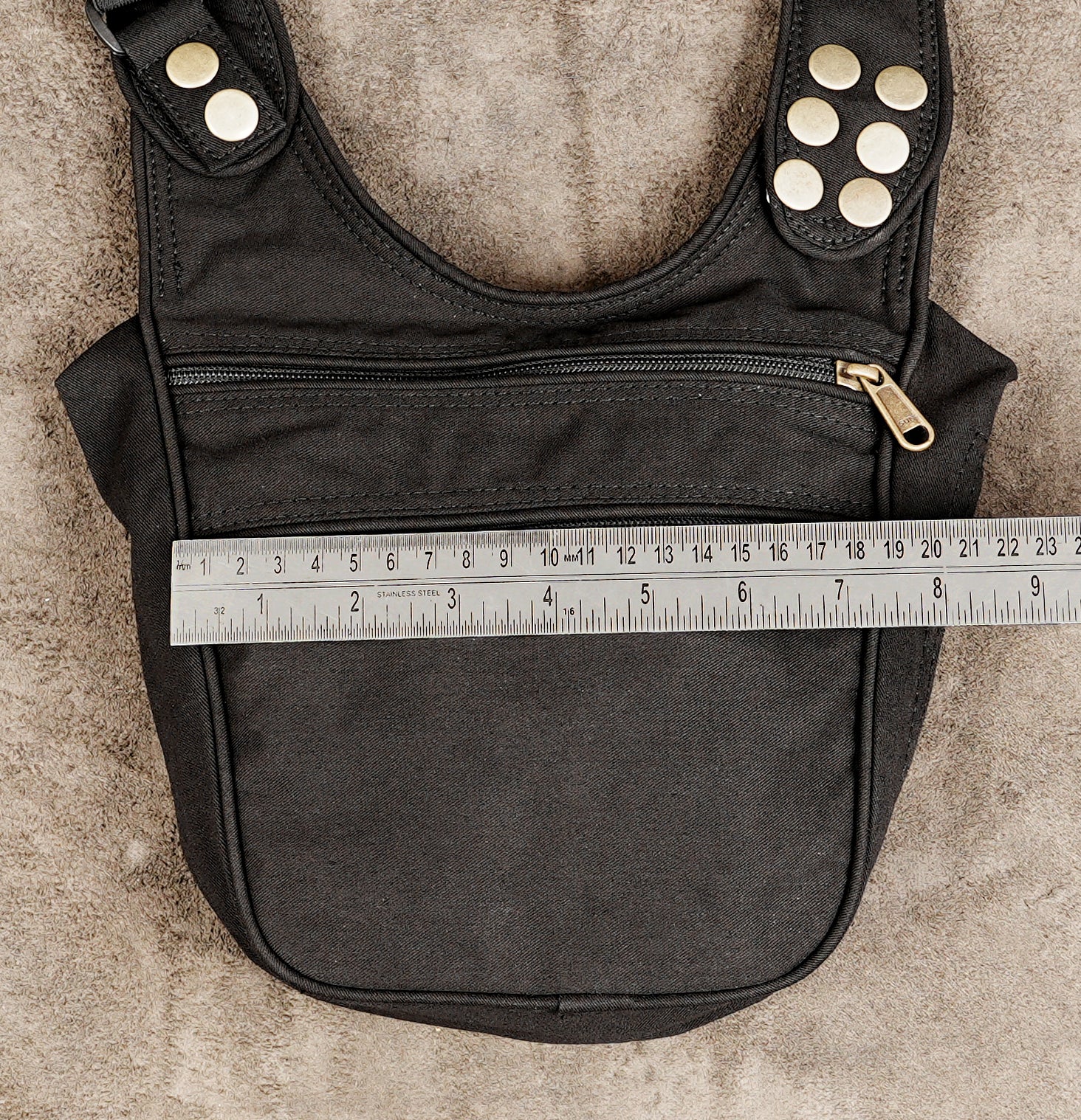 A black fabric shoulder bag with silver-tone metal studs and a front zip pocket
