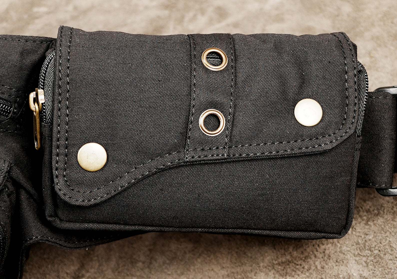 Black cotton hip bag with brass zippers and studded flap pocket