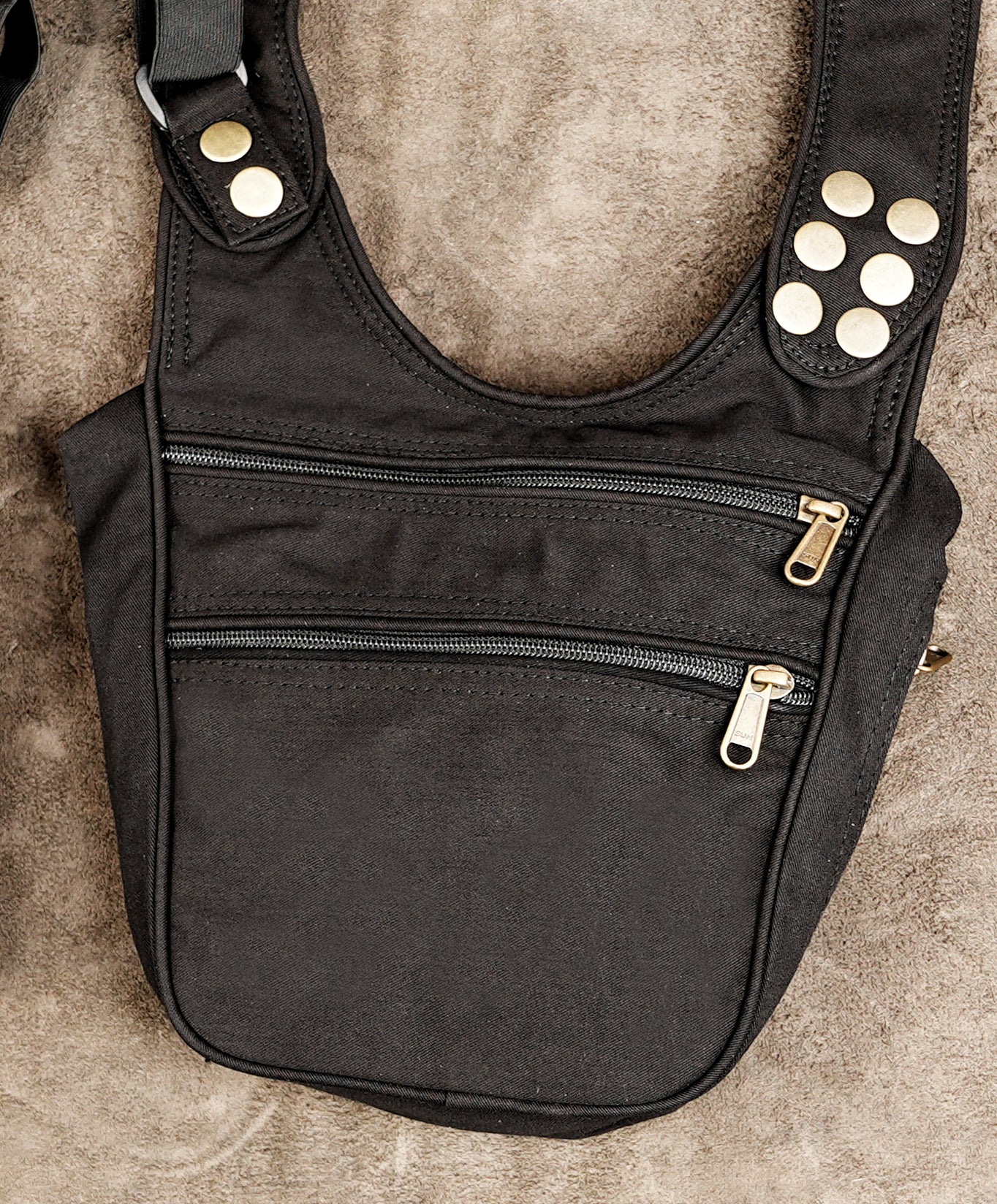 Black canvas shoulder bag with multiple zippered pockets and gold-tone hardware