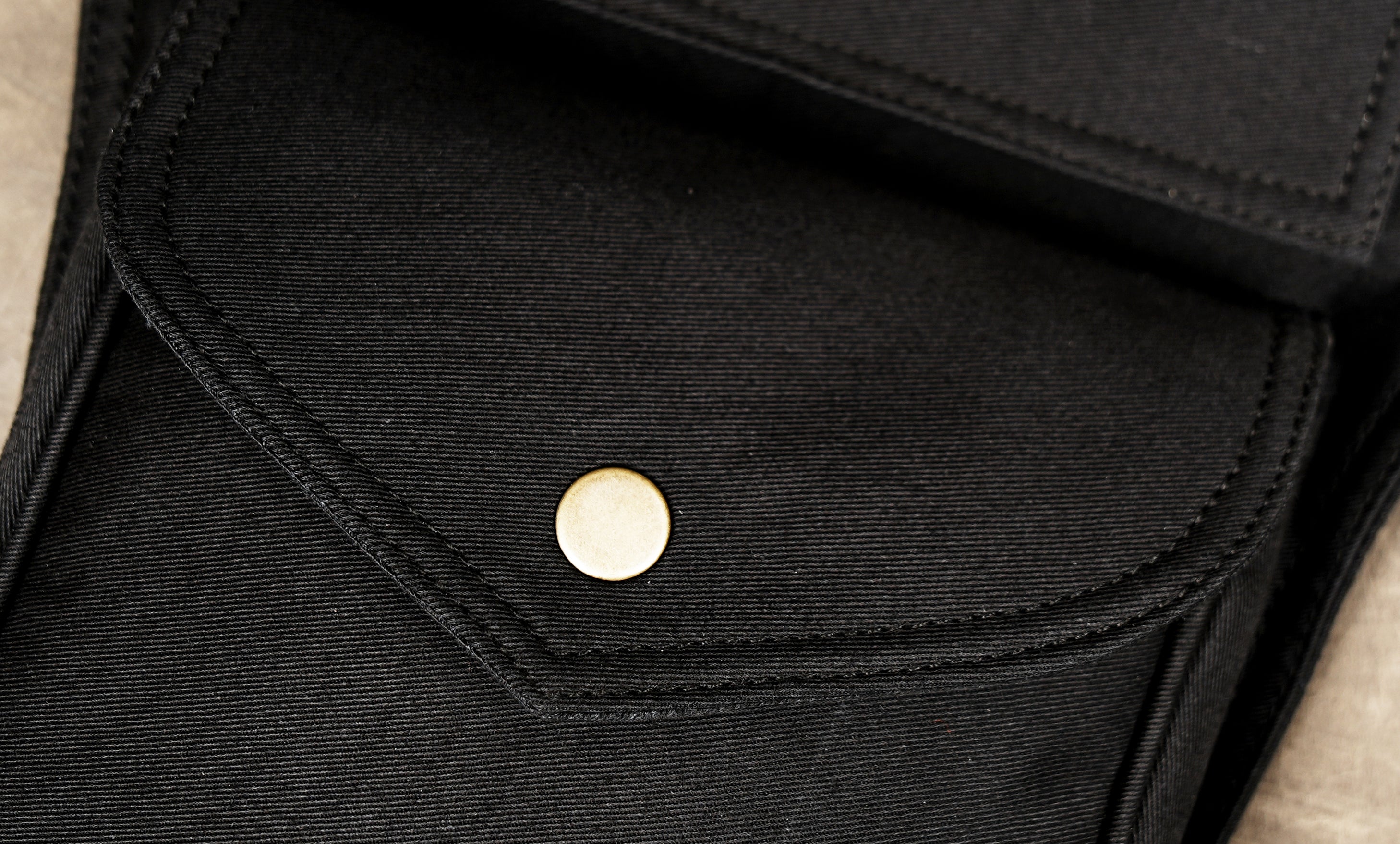 Black cotton canvas utility belt bag with front pocket and snap closure.