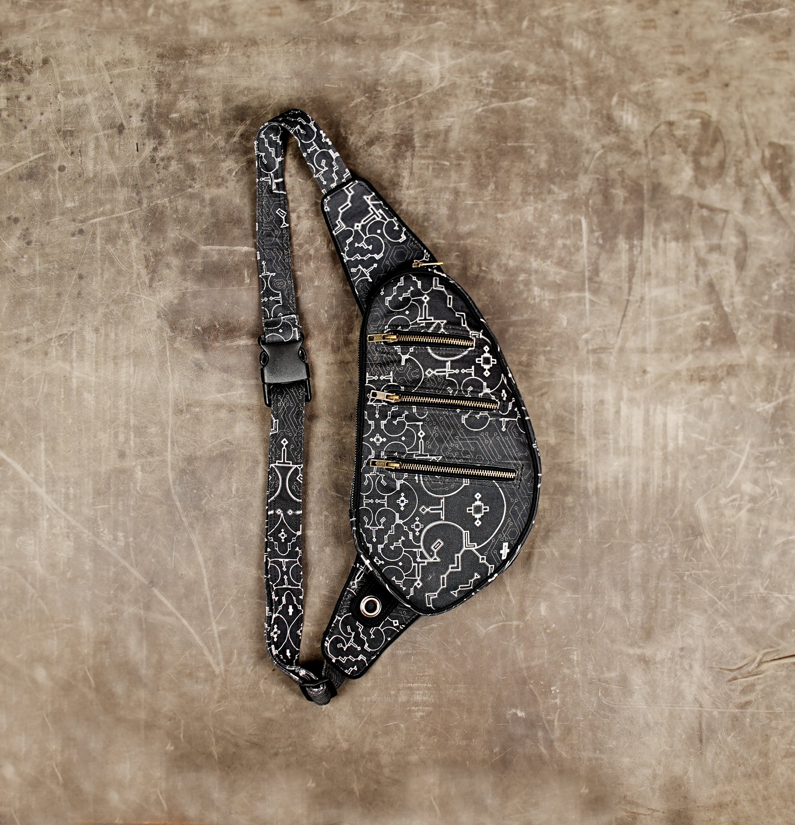 Black cotton shoulder bag with white geometric Shipibo-inspired print and three brass zipper pockets